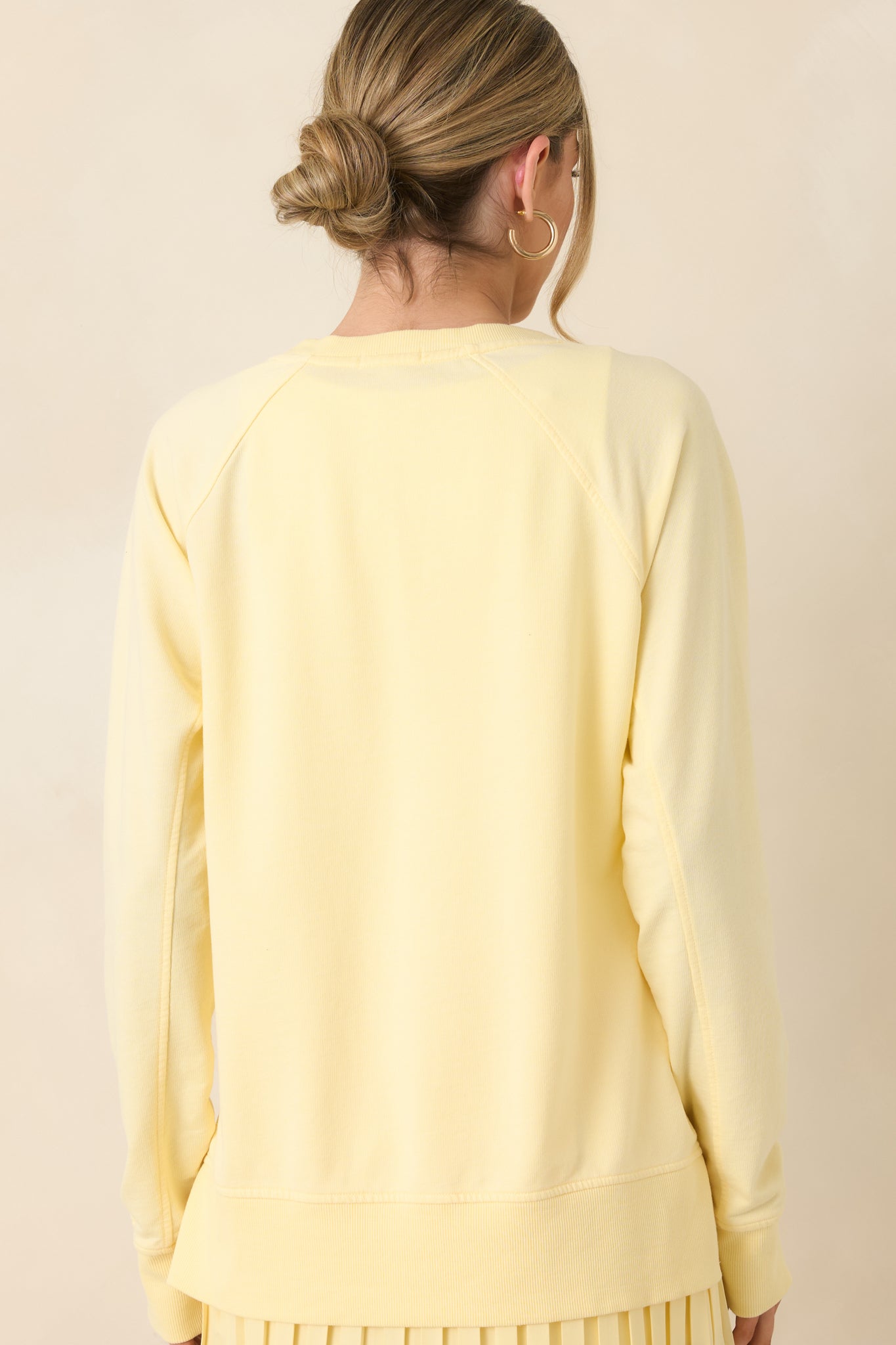 Yellow sweatshirt shown from the back with relaxed drape and clean raglan sleeve lines