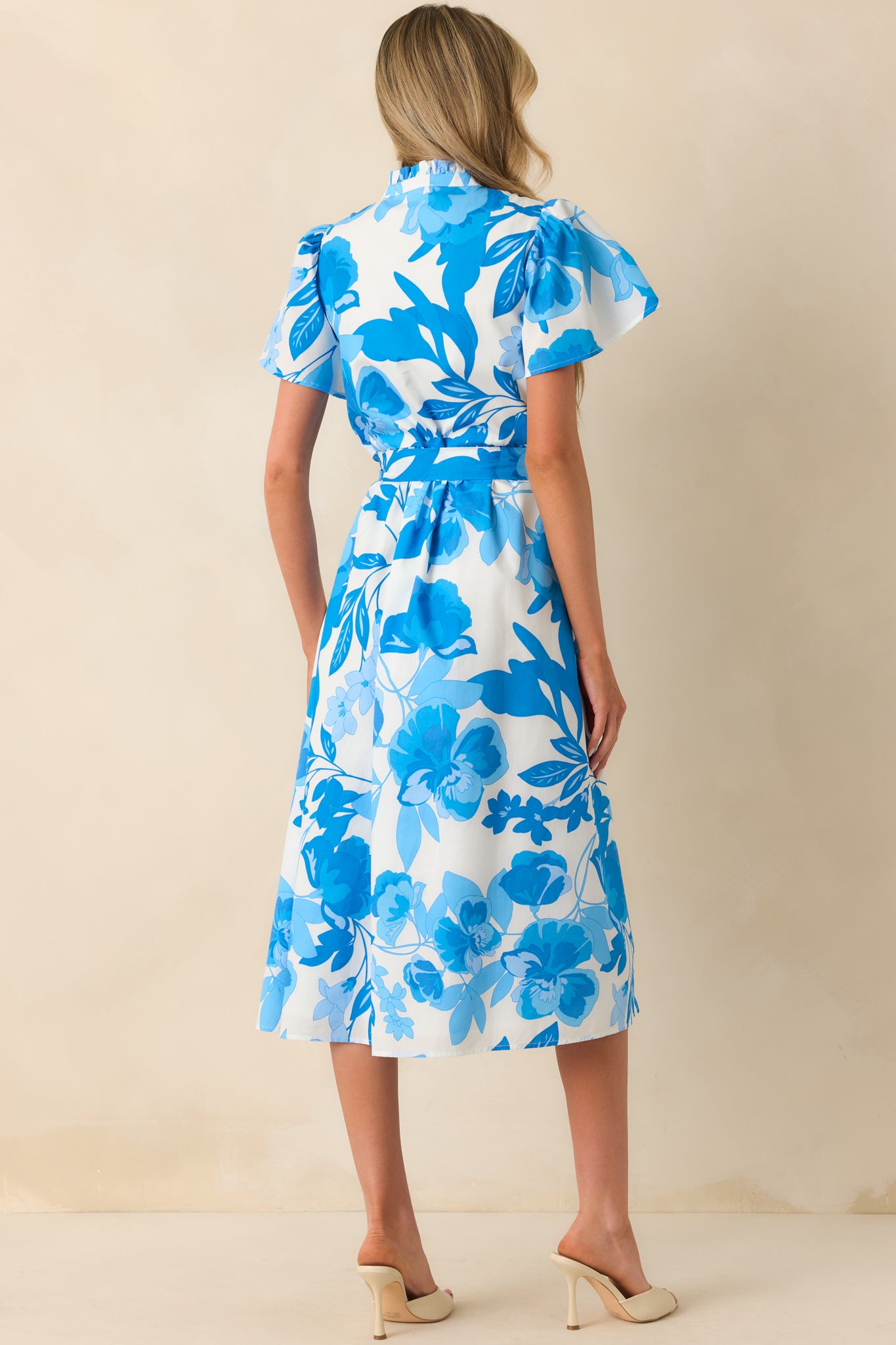 A view from behind featuring the continued floral print, softly defined waist, and short sleeves.