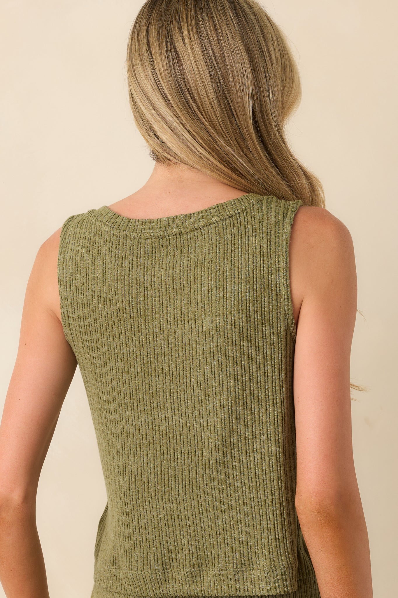 A view from behind of the olive green top showing the sleeveless design and relaxed fit with a smooth finish.