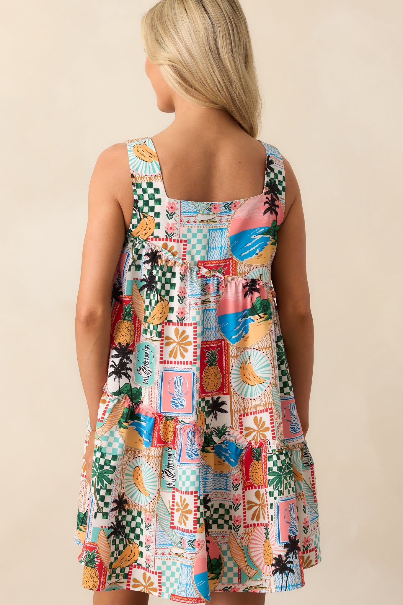 A view from behind of the tropical mini dress highlighting the ruffled hem and smooth, flowing fabric.