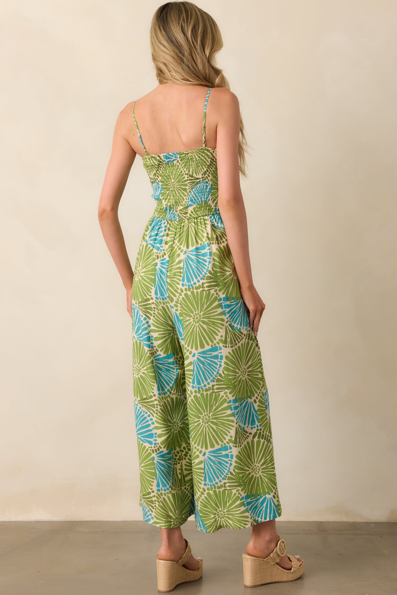 A view from behind showing the fully smocked back, adjustable straps, and wide-leg cut of the floral jumpsuit.