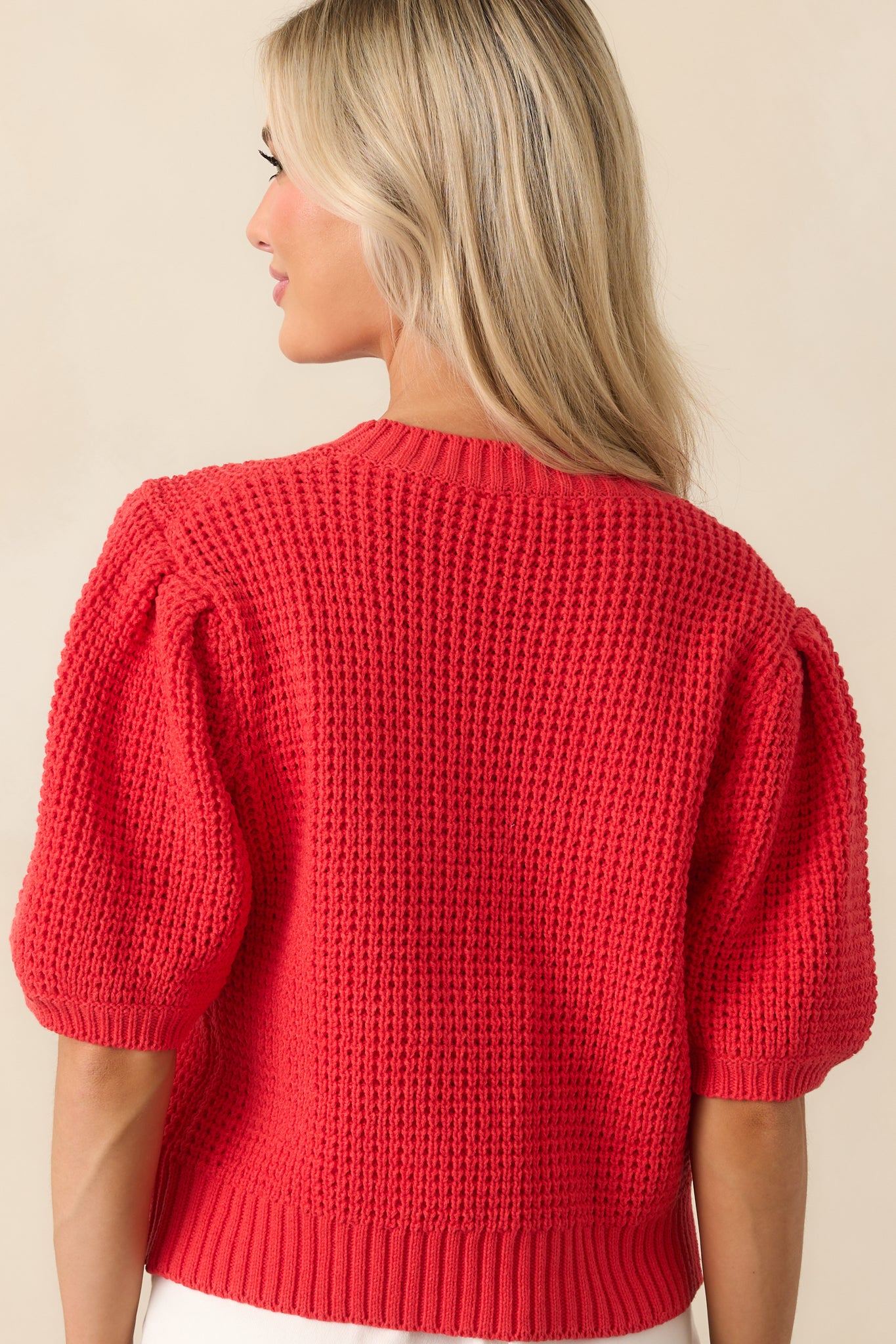 A view from behind showing the smooth knit texture, short sleeves, and ribbed hem of the navy sweater.