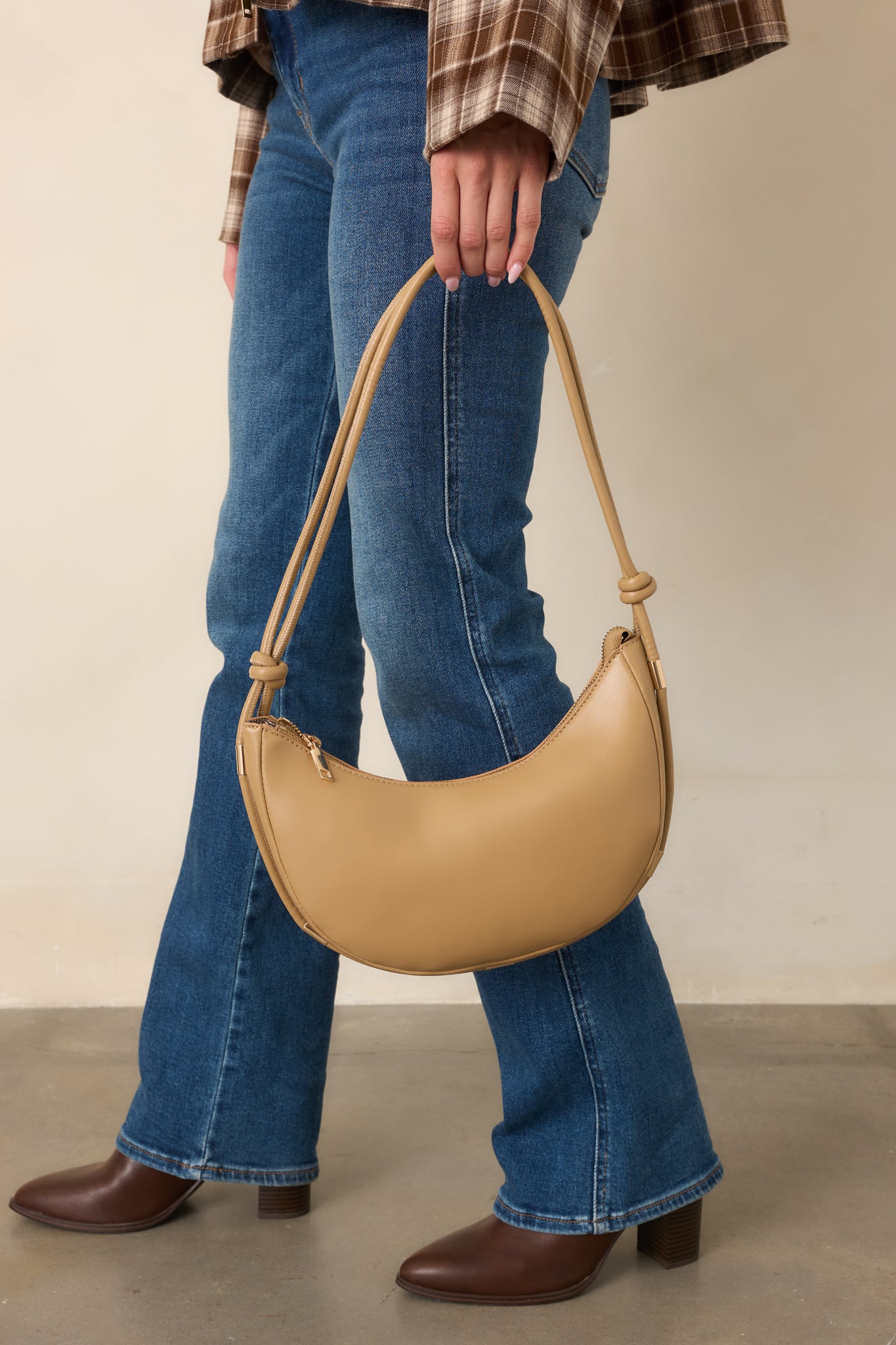 Beige handbag showcasing its adjustable knotted shoulder strap, gold-tone hardware, roomy single compartment, and polished everyday silhouette.