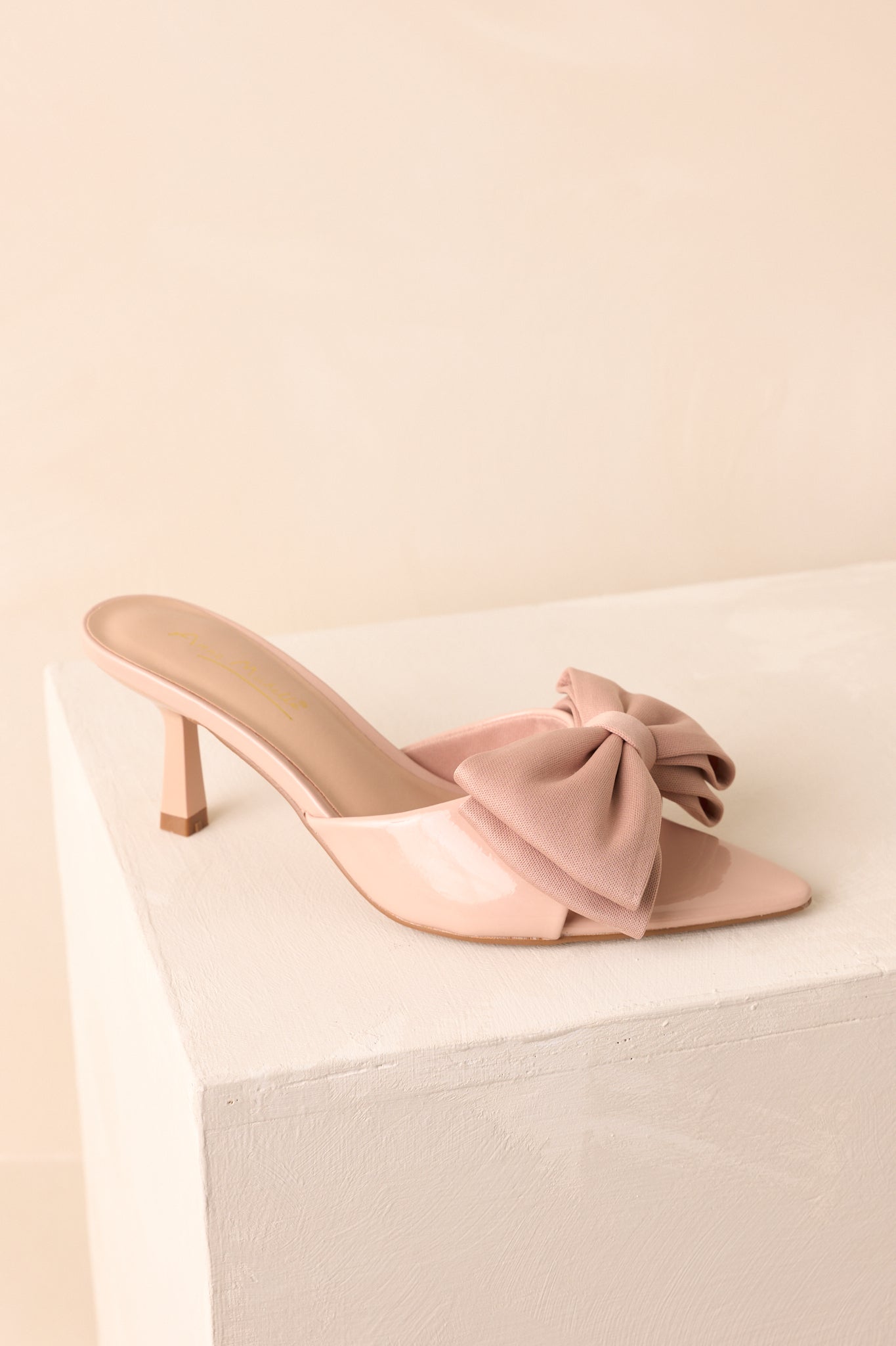 Angled view of the beige bow mule highlighting the pointed toe.