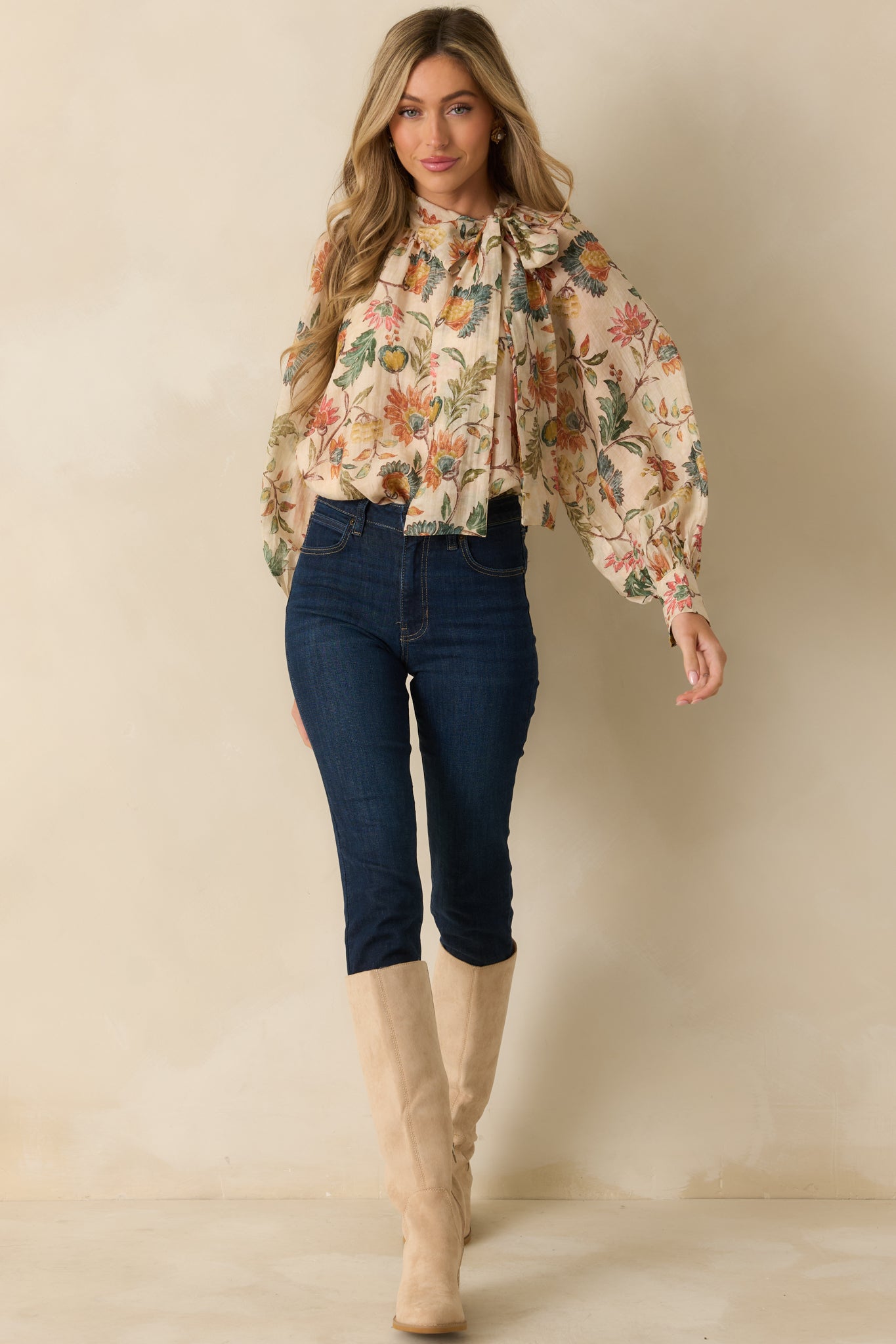 Beige blouse with allover floral print, bow tie neckline, and flowing long sleeves in a relaxed silhouette.