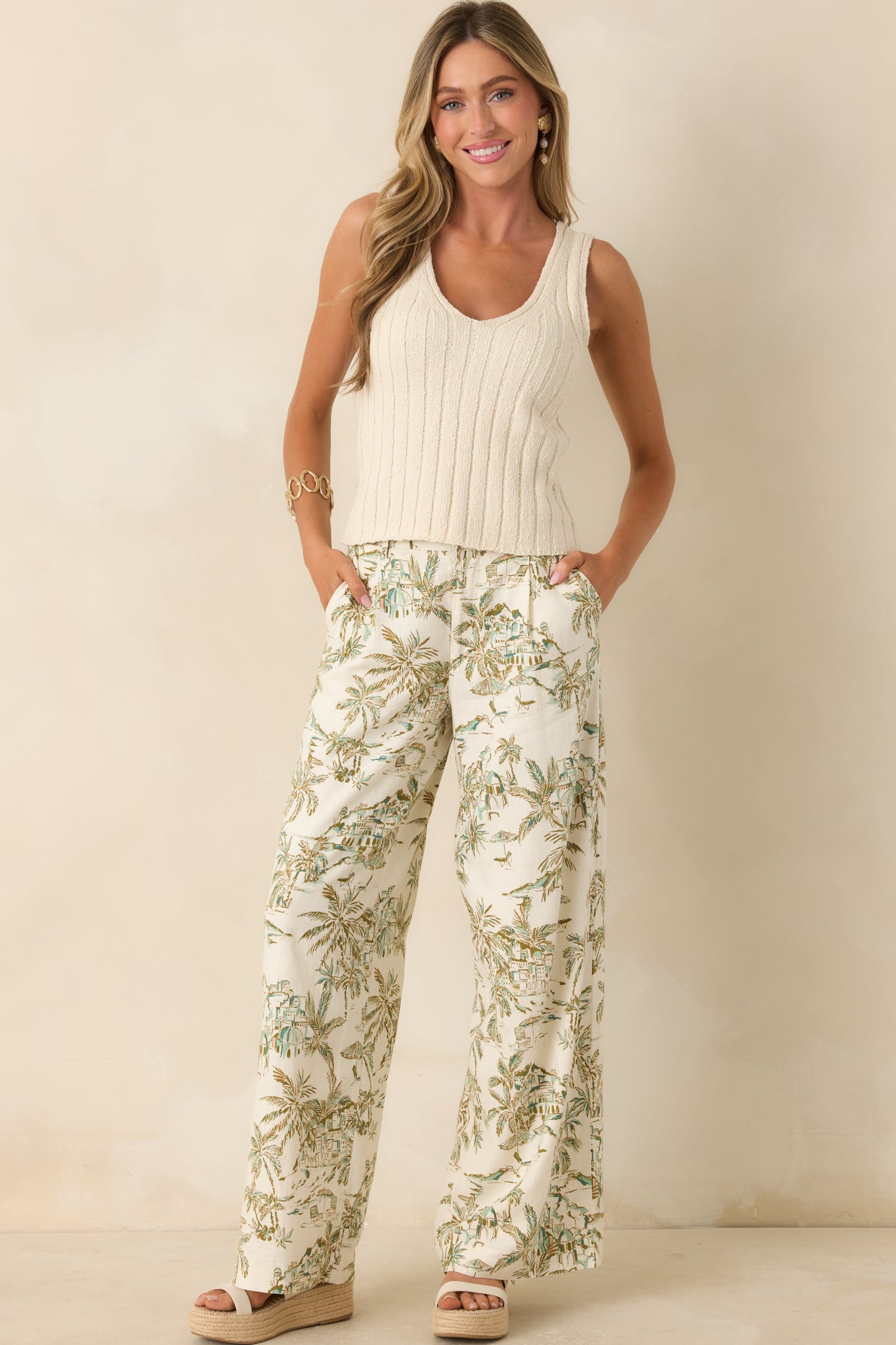 Beige and green printed pants featuring a structured button-front closure and relaxed wide-leg drape in soft midweight linen blend fabric.