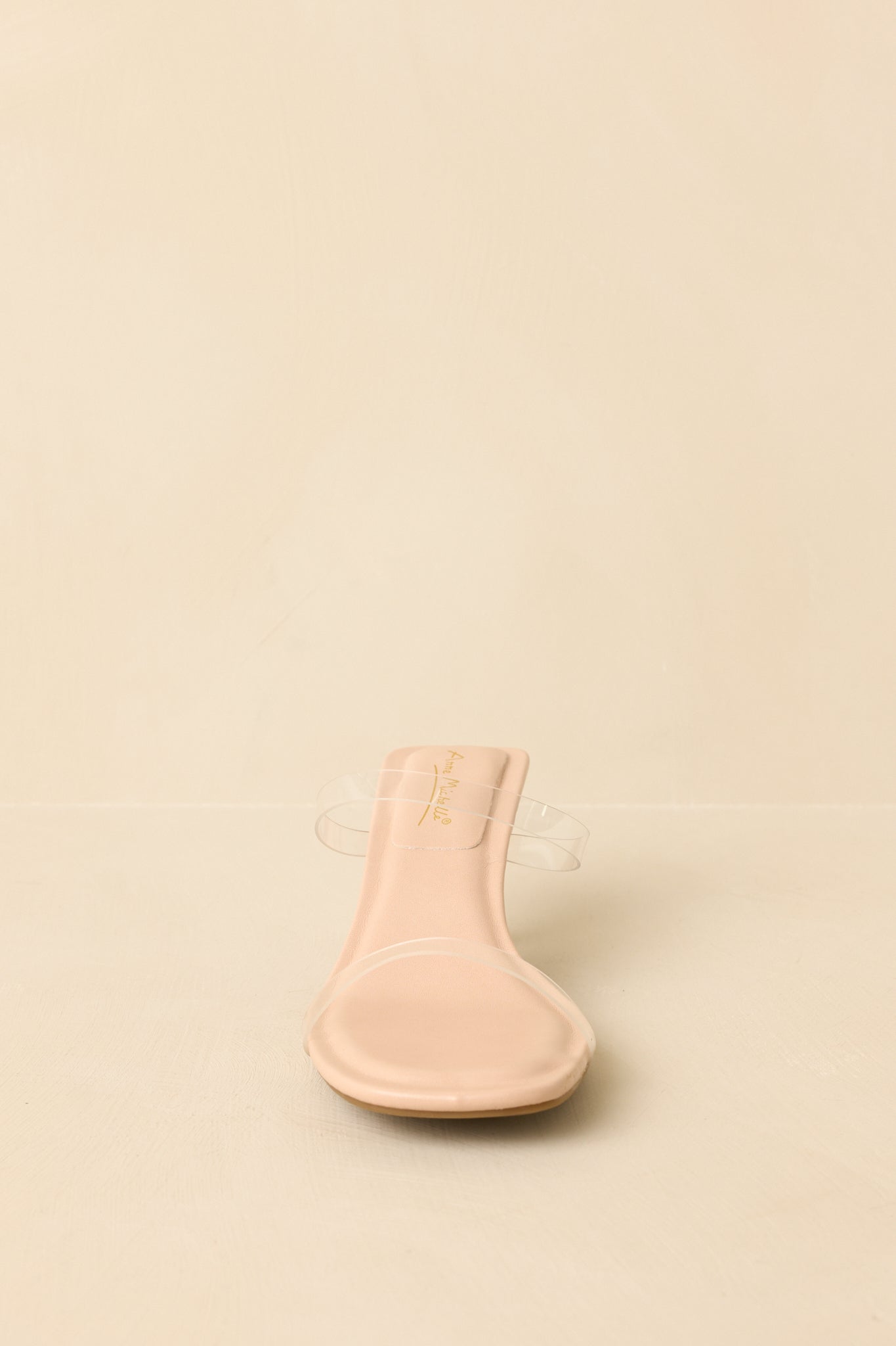 Beige heels angled to emphasize the transparent heel and clean open-toe shape.