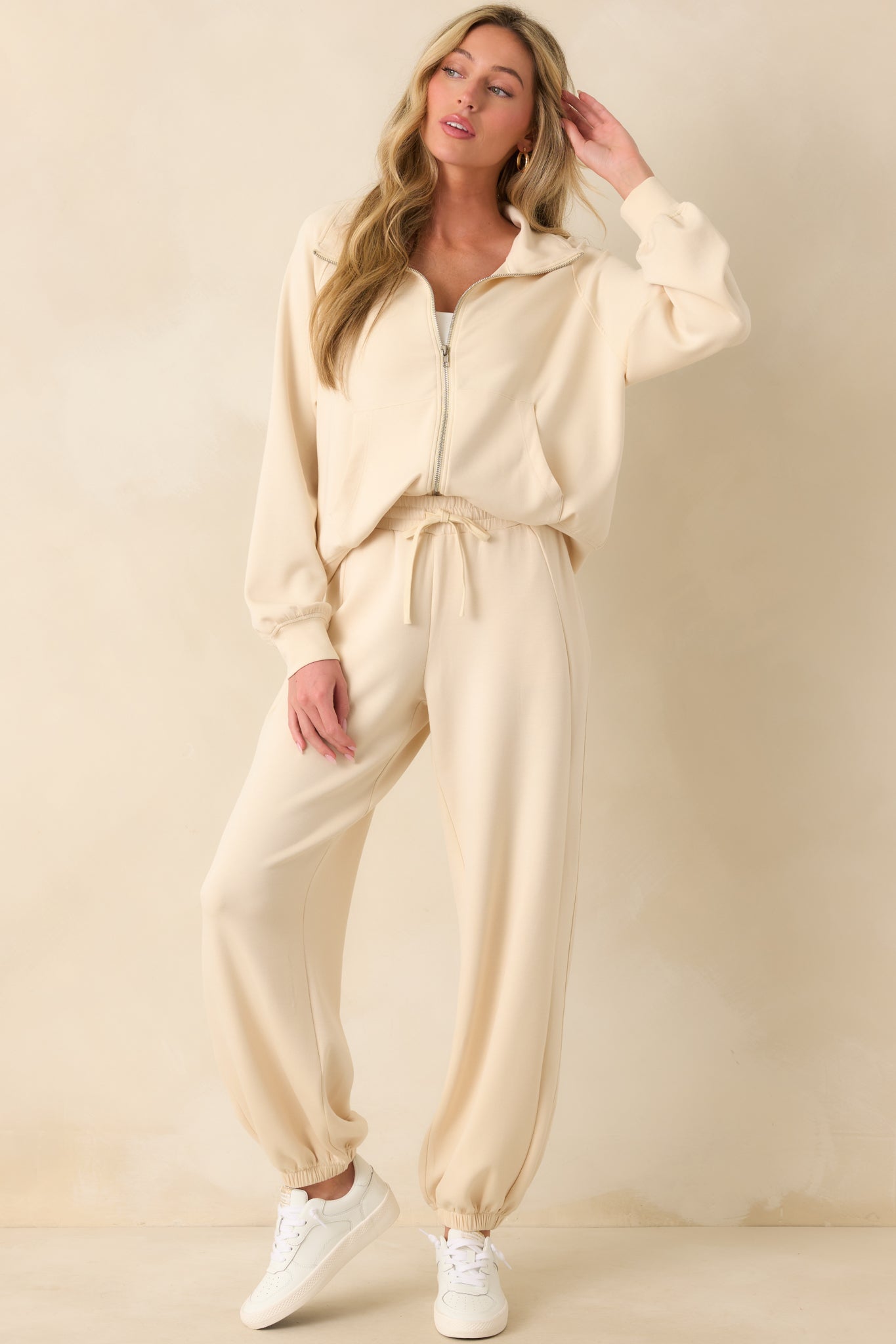 A full front view of the ecru joggers showcasing the thick elastic waistband, self-tie drawstring, and relaxed silhouette.