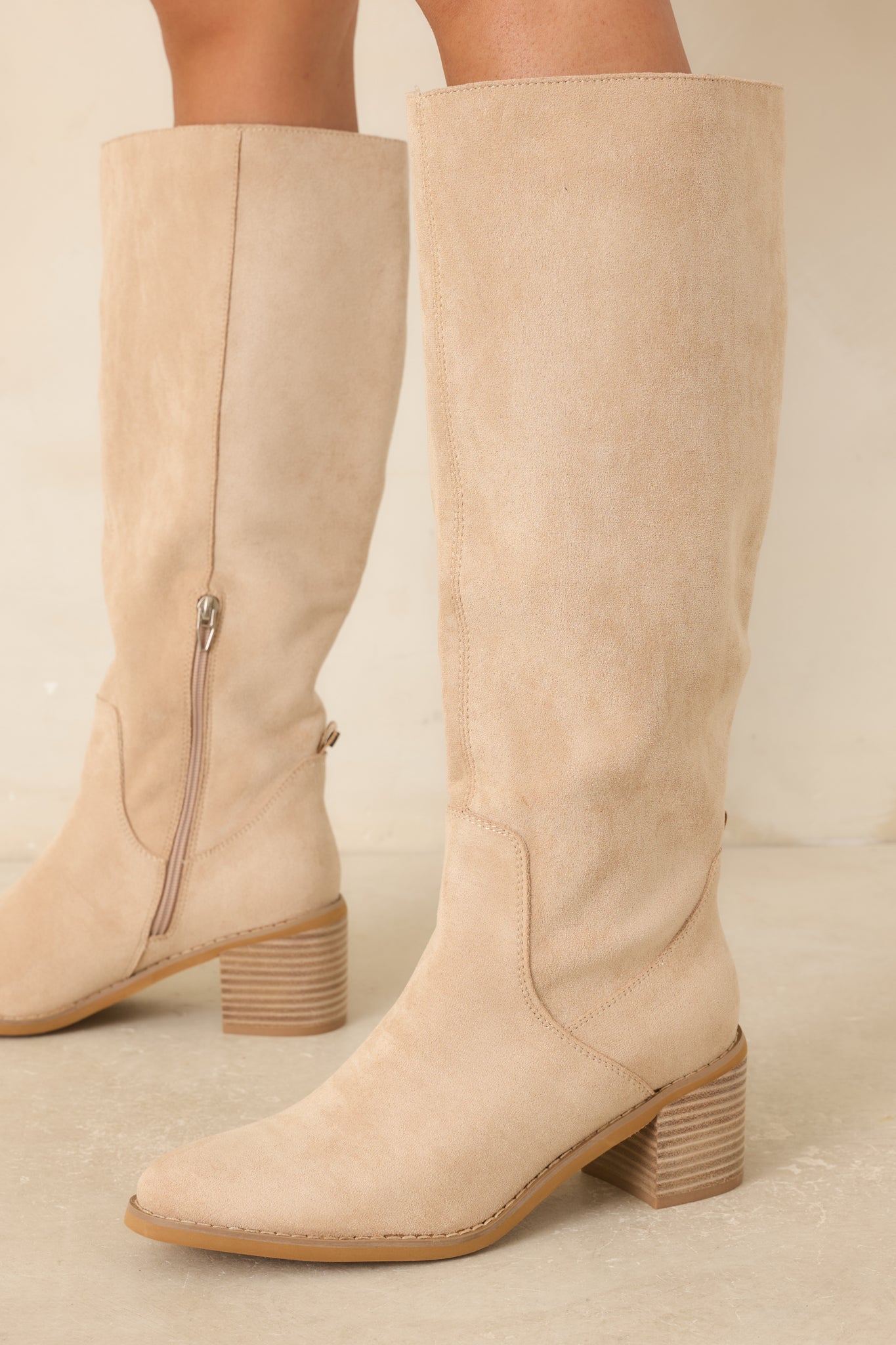 Beige knee-high boots featuring a soft faux suede finish, almond toe, and stacked block heel.