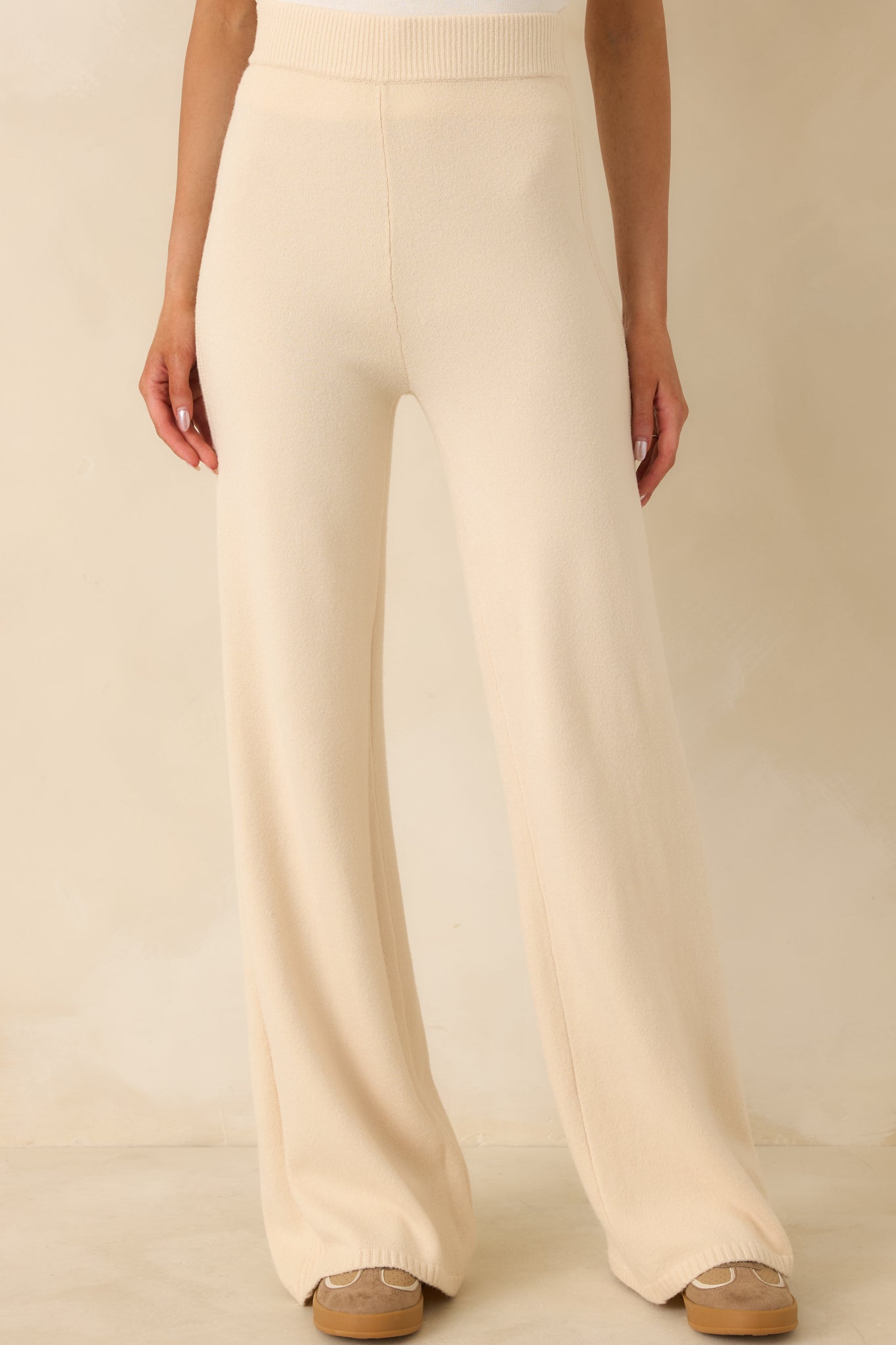 Beige knit pants with wide-leg silhouette and high-rise elastic waistband.