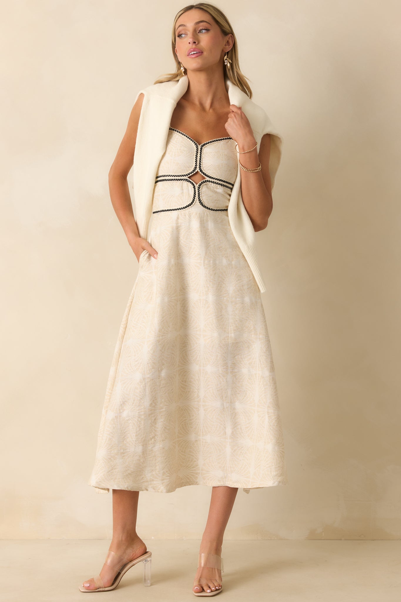 Light beige maxi dress with a sweetheart neckline, black braided contrast trim, and front cutout waist detail.