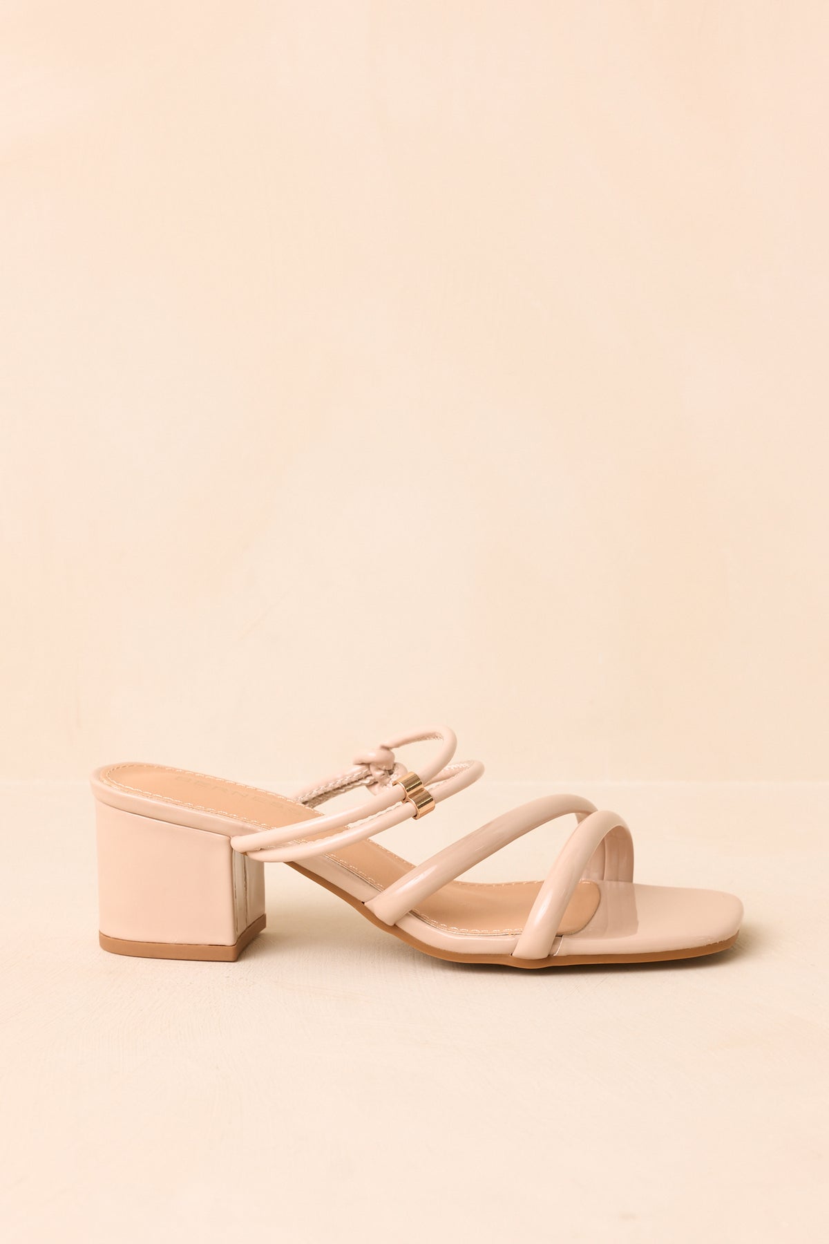 Beige heels showing the open square toe and smooth crossed straps.