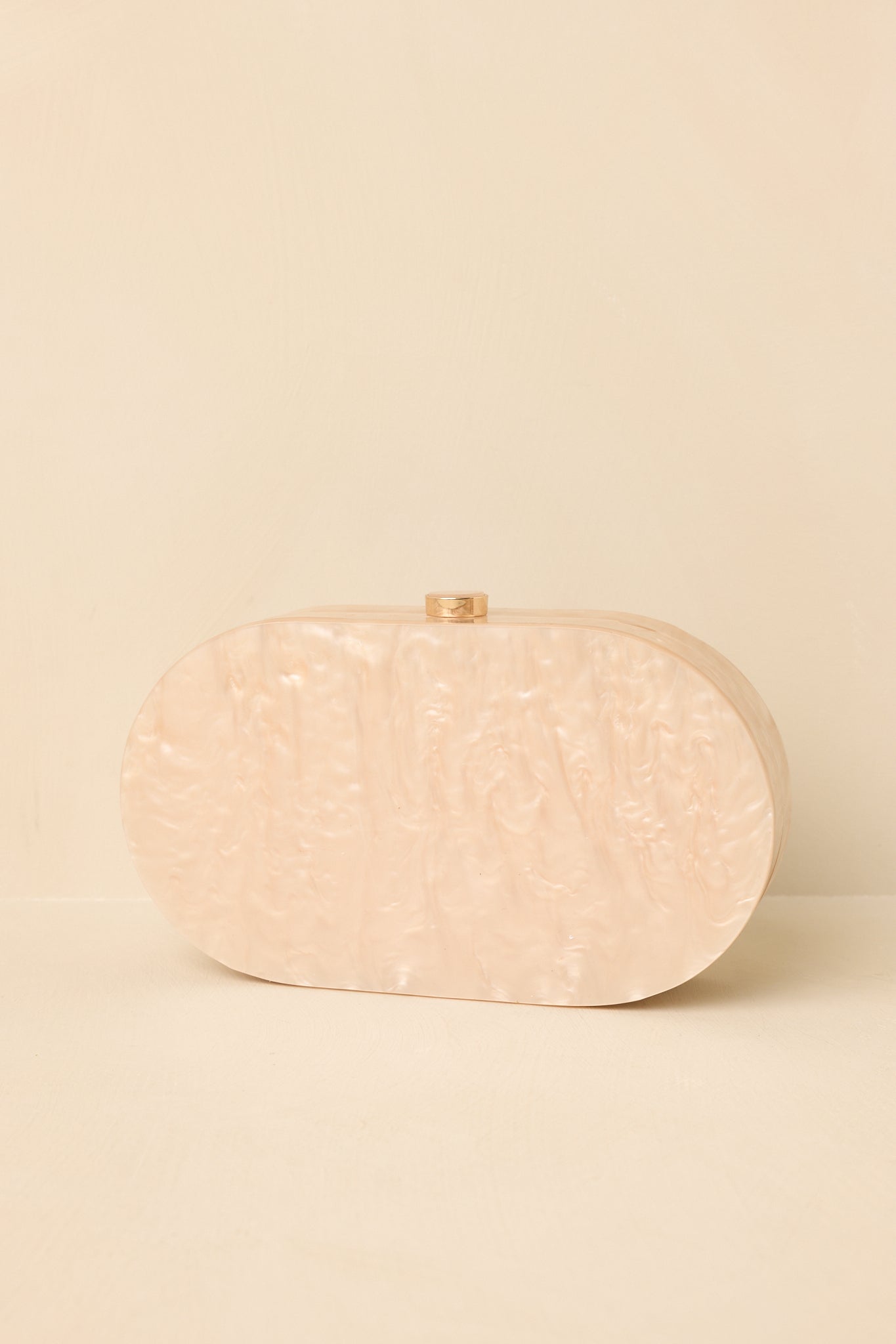 Back view of the beige pearlescent clutch showcasing the smooth oval silhouette.