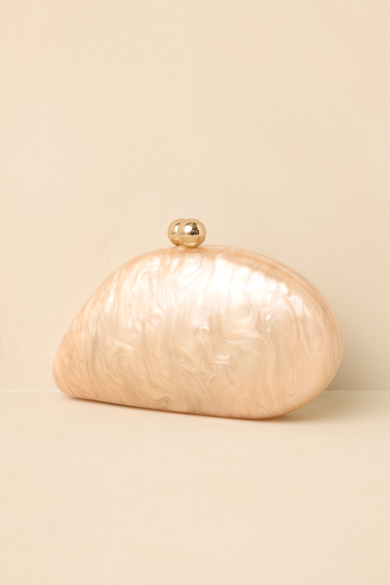 Oval marble clutch showcasing a polished beige finish, magnetic closure, detachable gold chain, and versatile design.