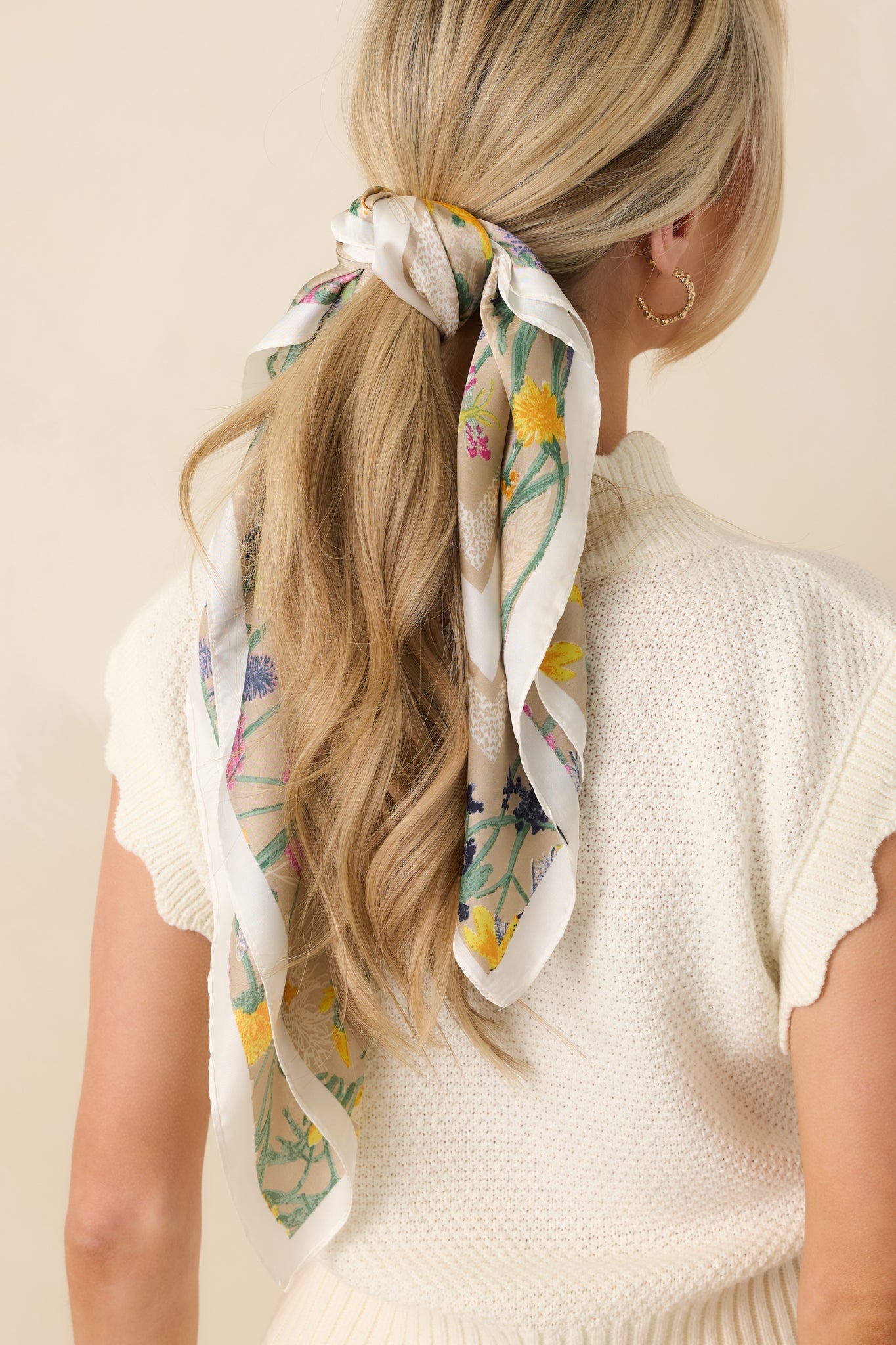 Cropped view of the beige scarf focusing on the vibrant floral motifs and smooth texture.