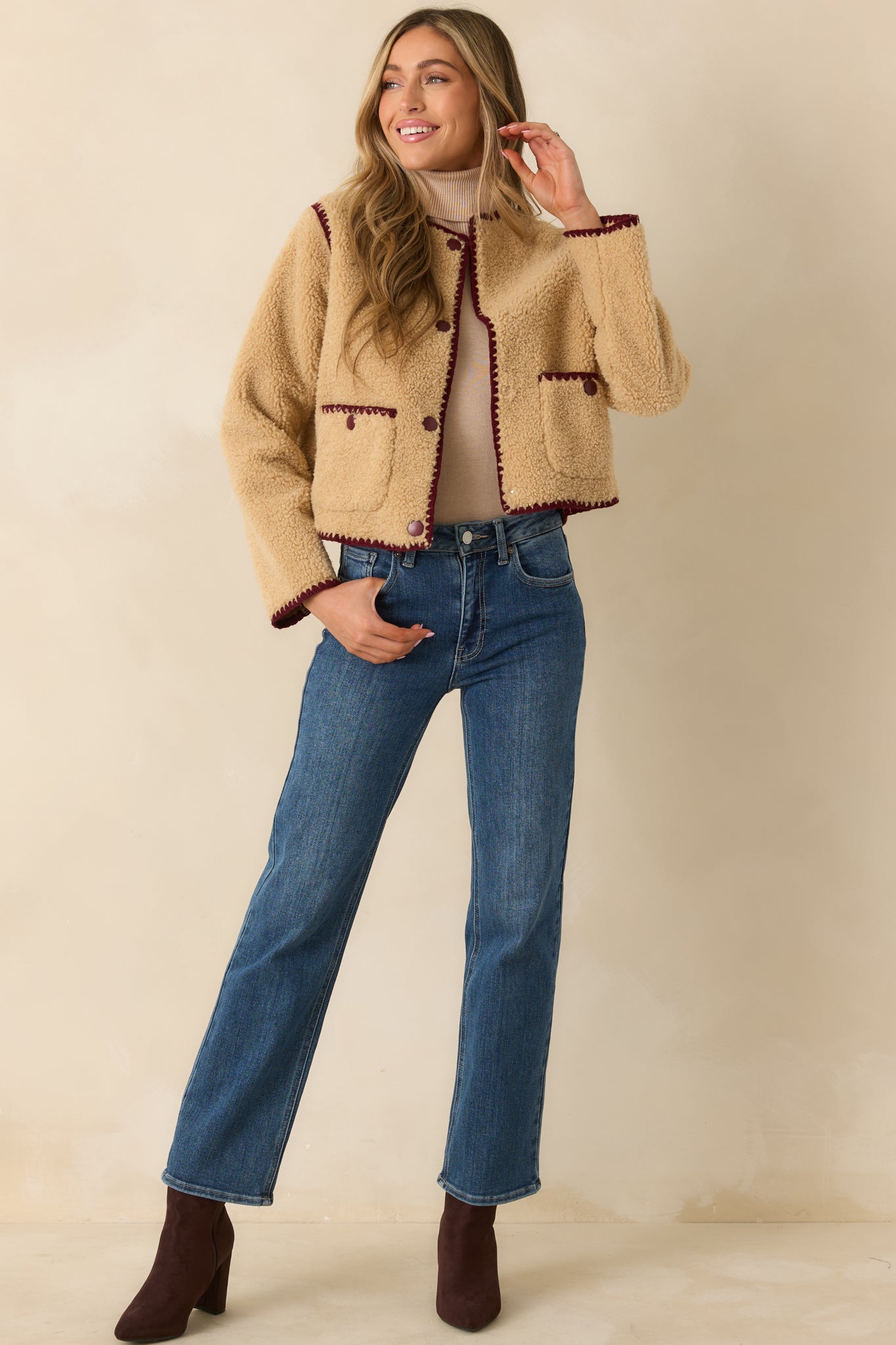 Beige sherpa jacket displaying its soft texture, burgundy trim, and easy relaxed fit.