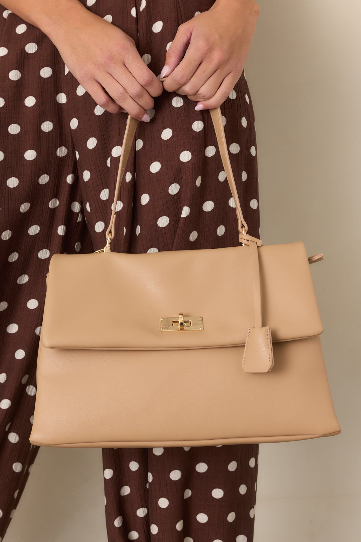 Smooth beige leather handbag with a structured silhouette and spacious compartmented design.