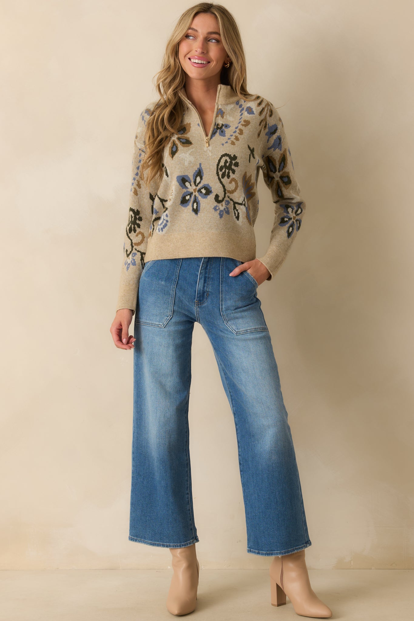 Long-sleeve beige sweater featuring ribbed hem, multicolor floral print, and a functional front zipper.