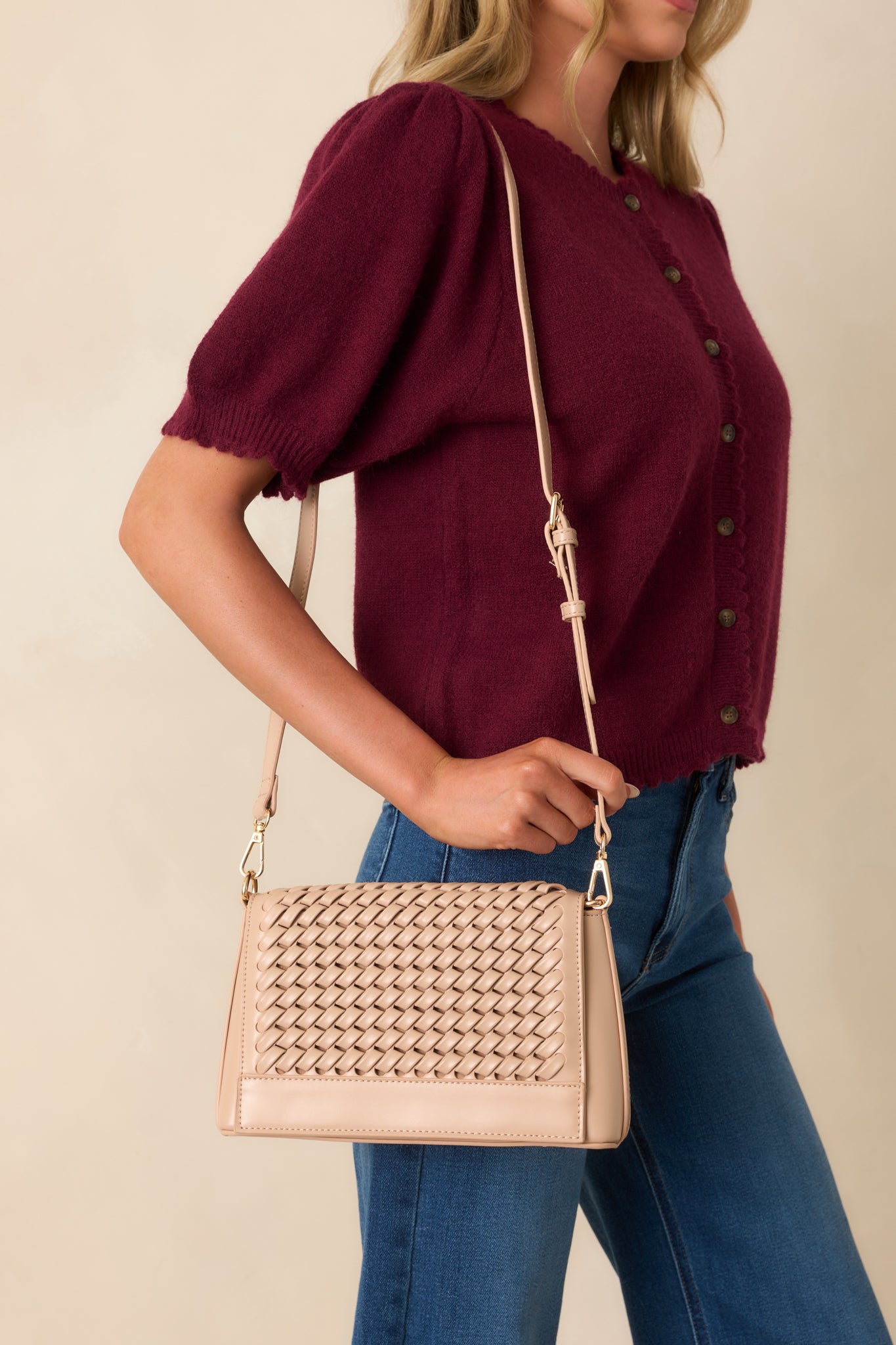 A full view of the beige handbag showcasing its woven faux leather texture and optional crossbody strap.