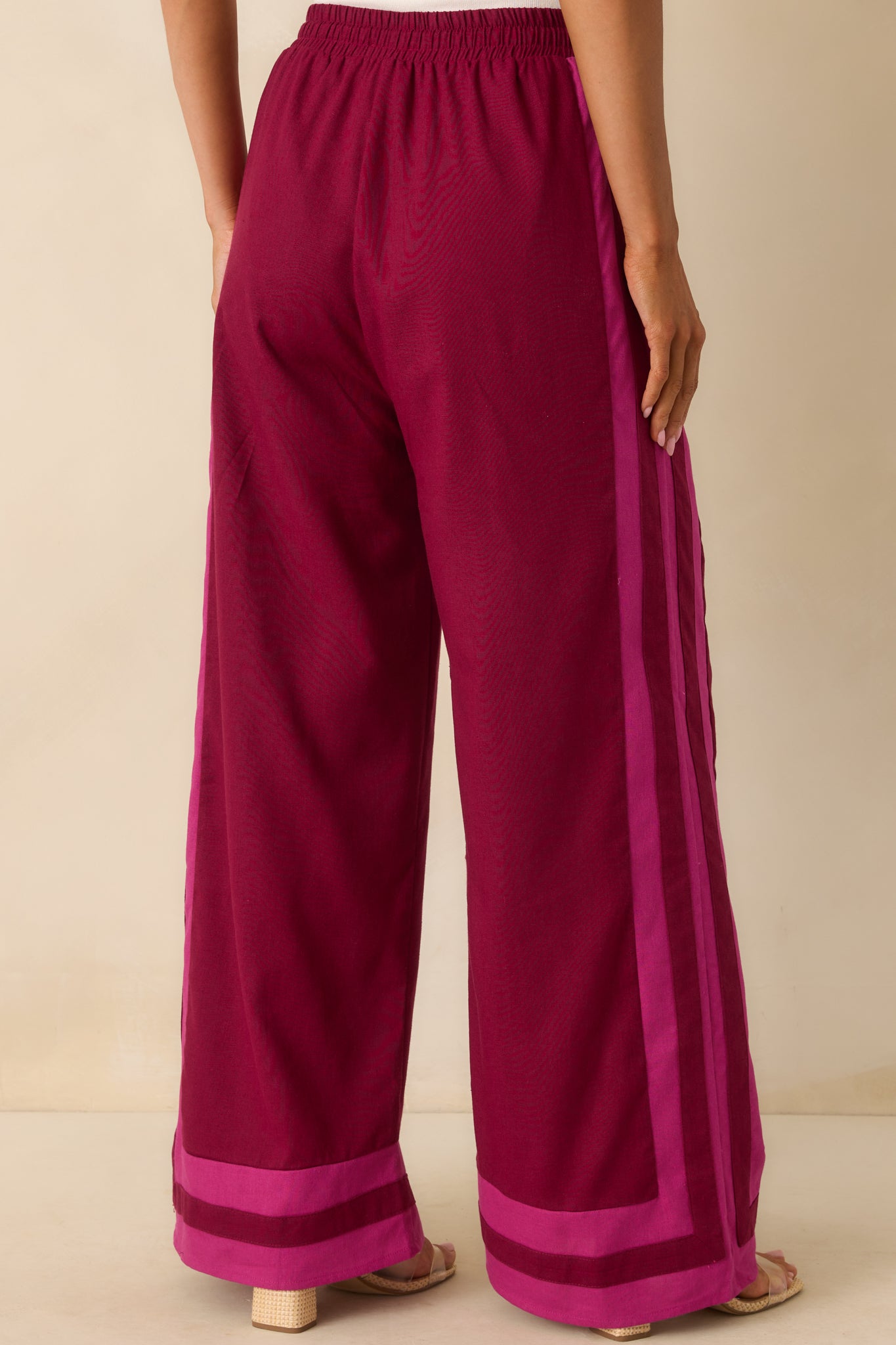 A view from behind showing the berry pants with wide legs, elastic waistband, and pink contrast trim along the back seams