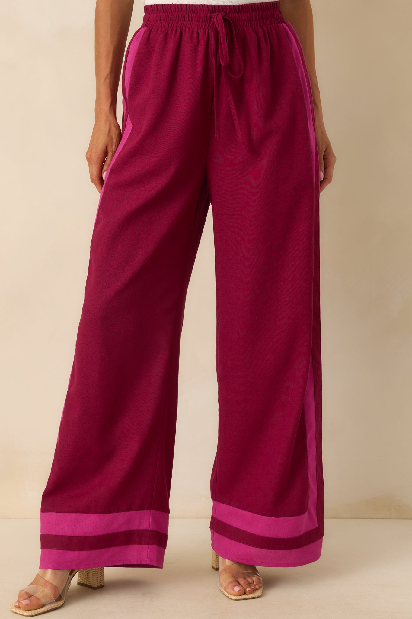 Front-focused cropped view of the berry pants with visible pink trim and wide-leg shape.