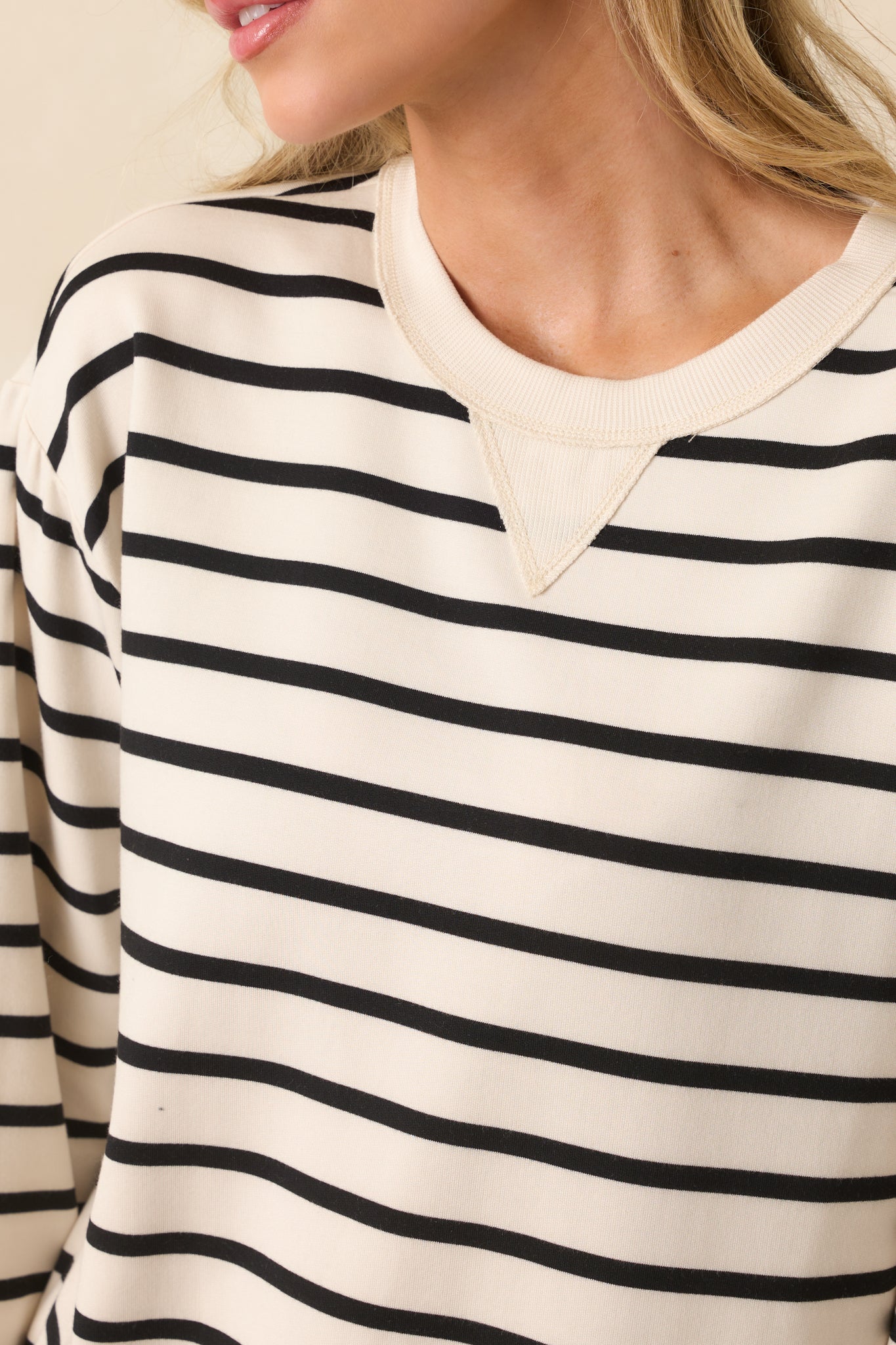 A detailed close-up of the neckline area capturing the v-stitch insert, ribbed collar, and stripe contrast.