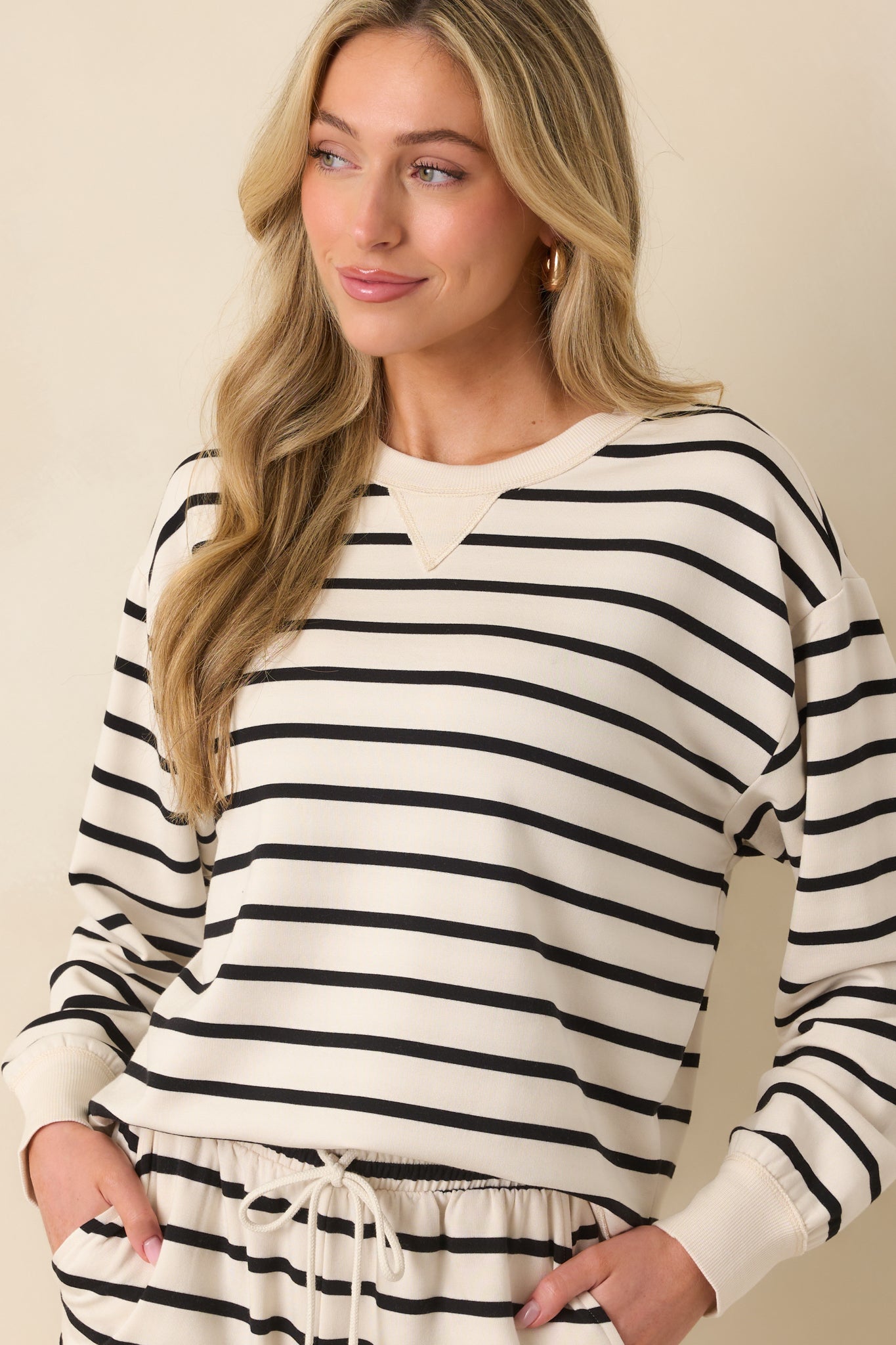 An angled crop shot focusing on the sleeve length and contrast of the ribbed cuff against the stripe pattern.