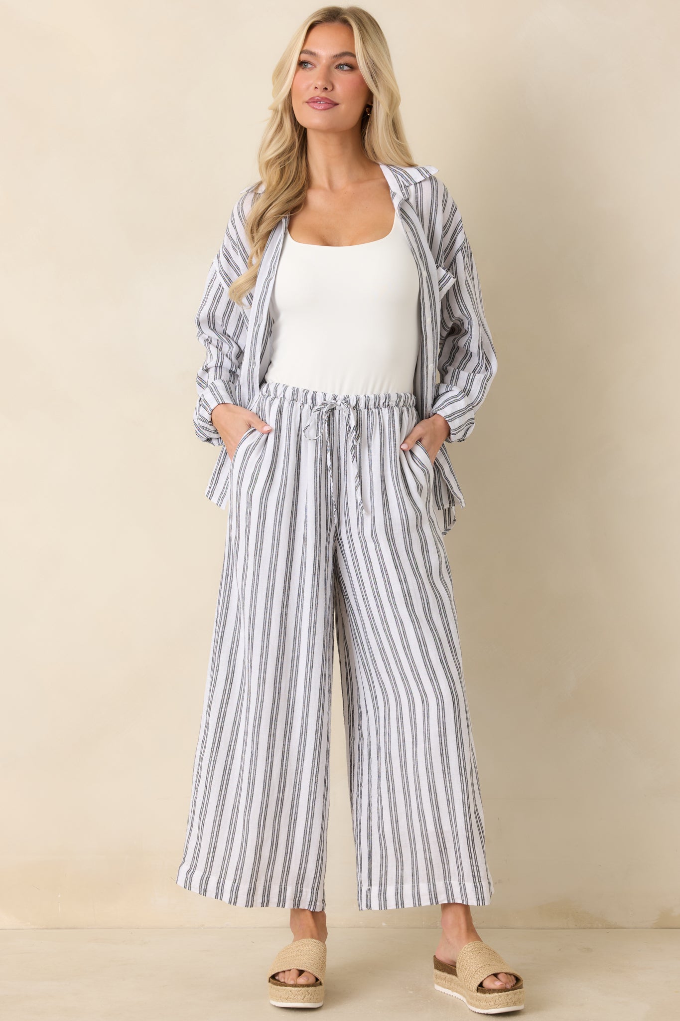 Full-length front view of black and white striped pants featuring a high-rise waist and wide-leg silhouette.