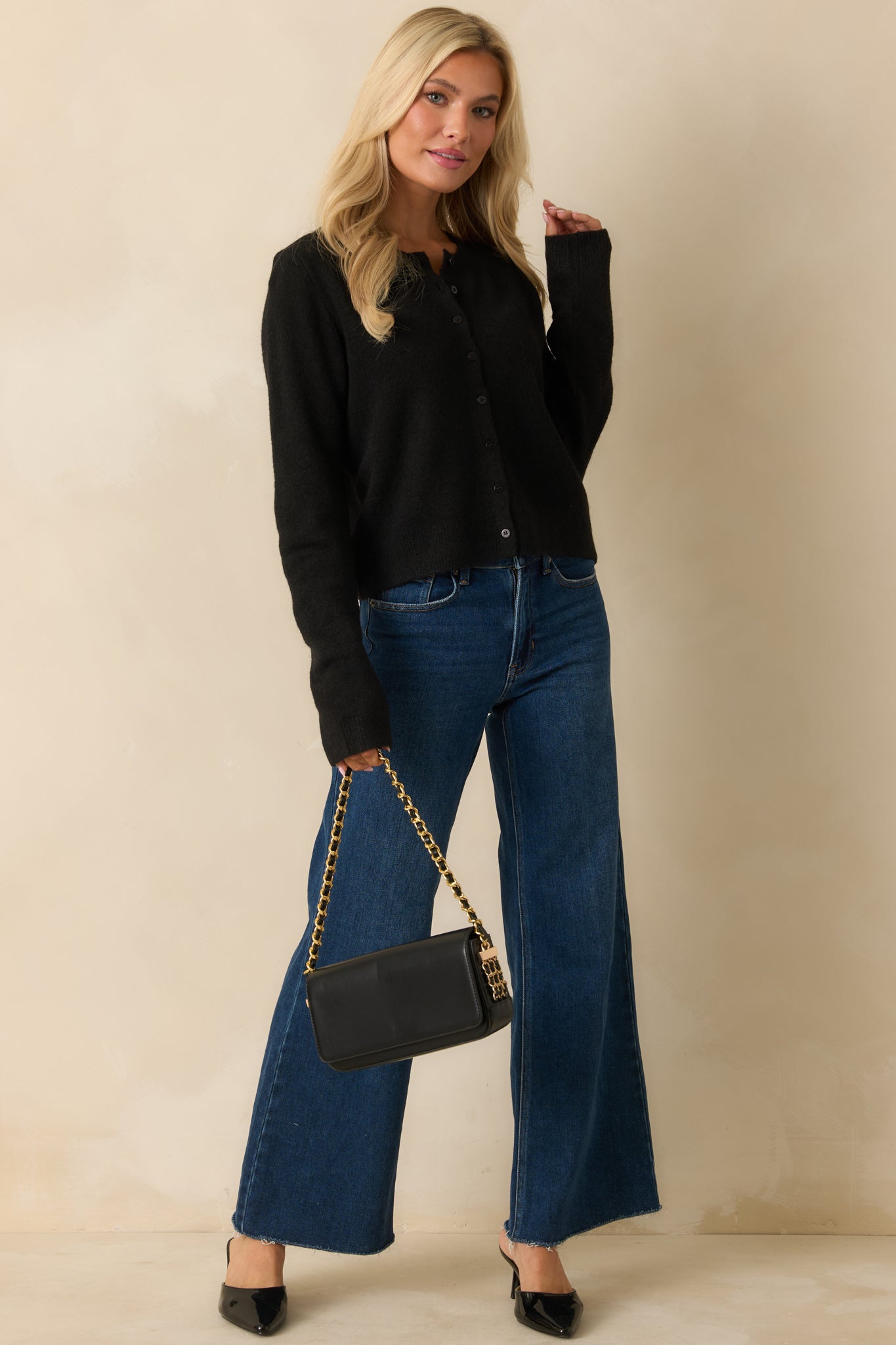 Button-front black cardigan highlighting its long sleeves, smooth knit, and neatly ribbed cuffs and hem.