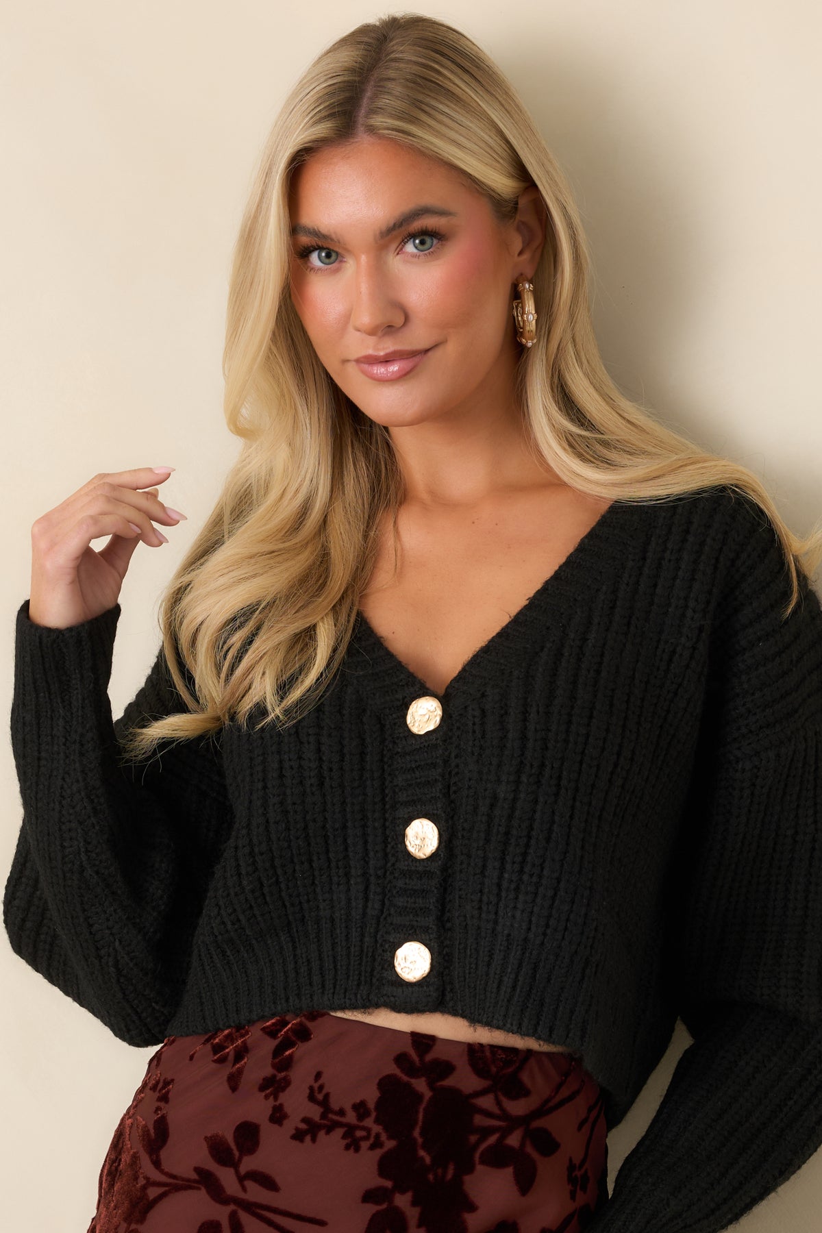 Deep V-neckline framed by chunky ribbing on the black cropped cardigan.