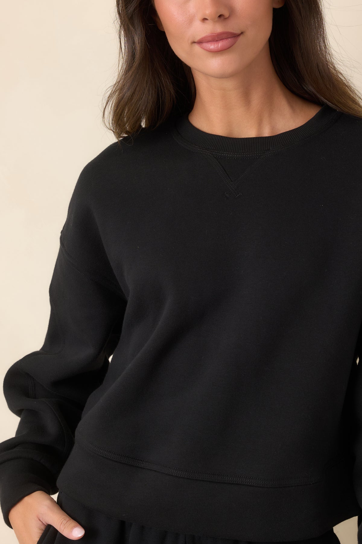 Close-up of the ribbed crew neckline, stitched V-inset, and soft cotton-blend fleece texture.