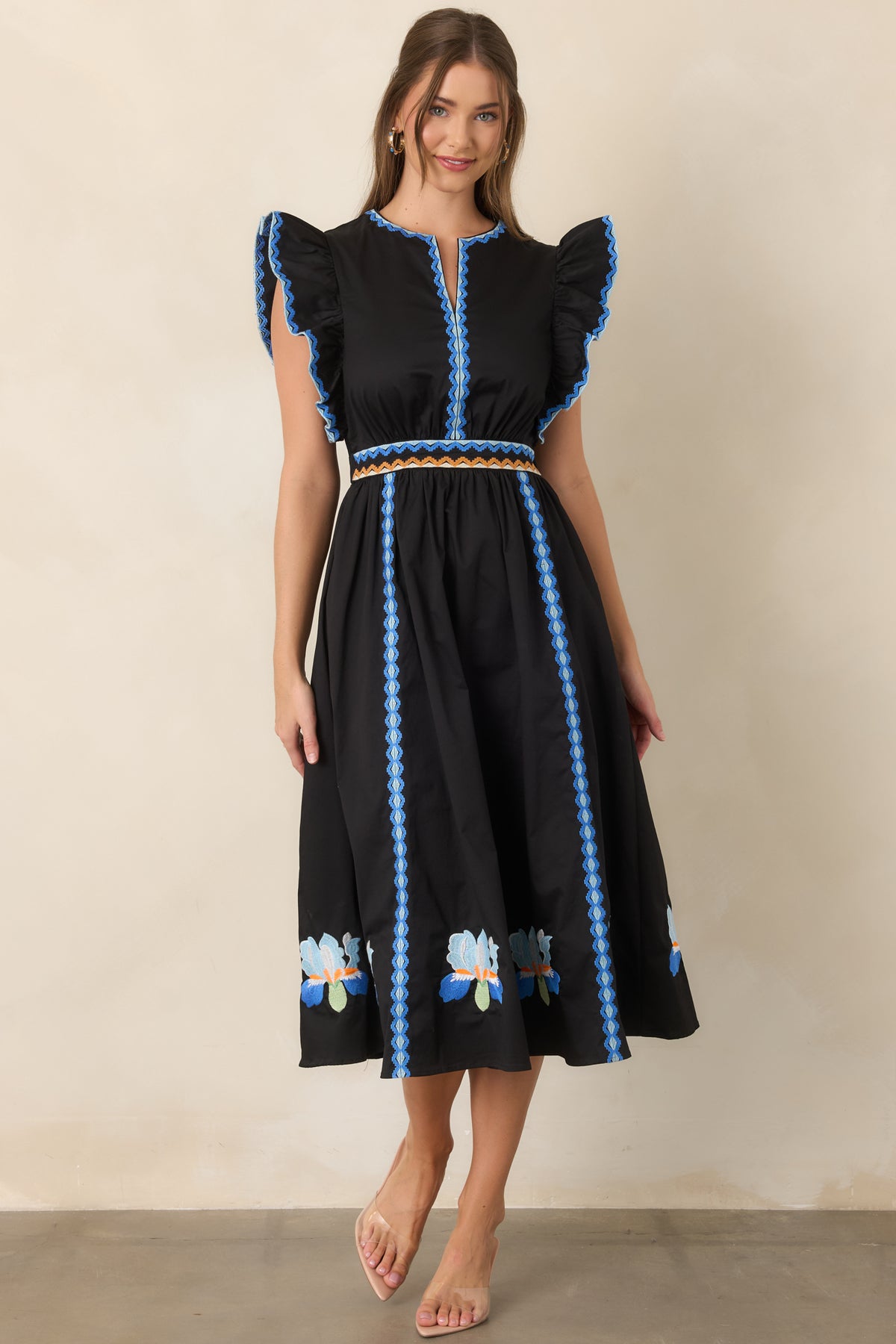 Black cotton-rich dress featuring colorful geometric embroidery and dramatic ruffle sleeves.