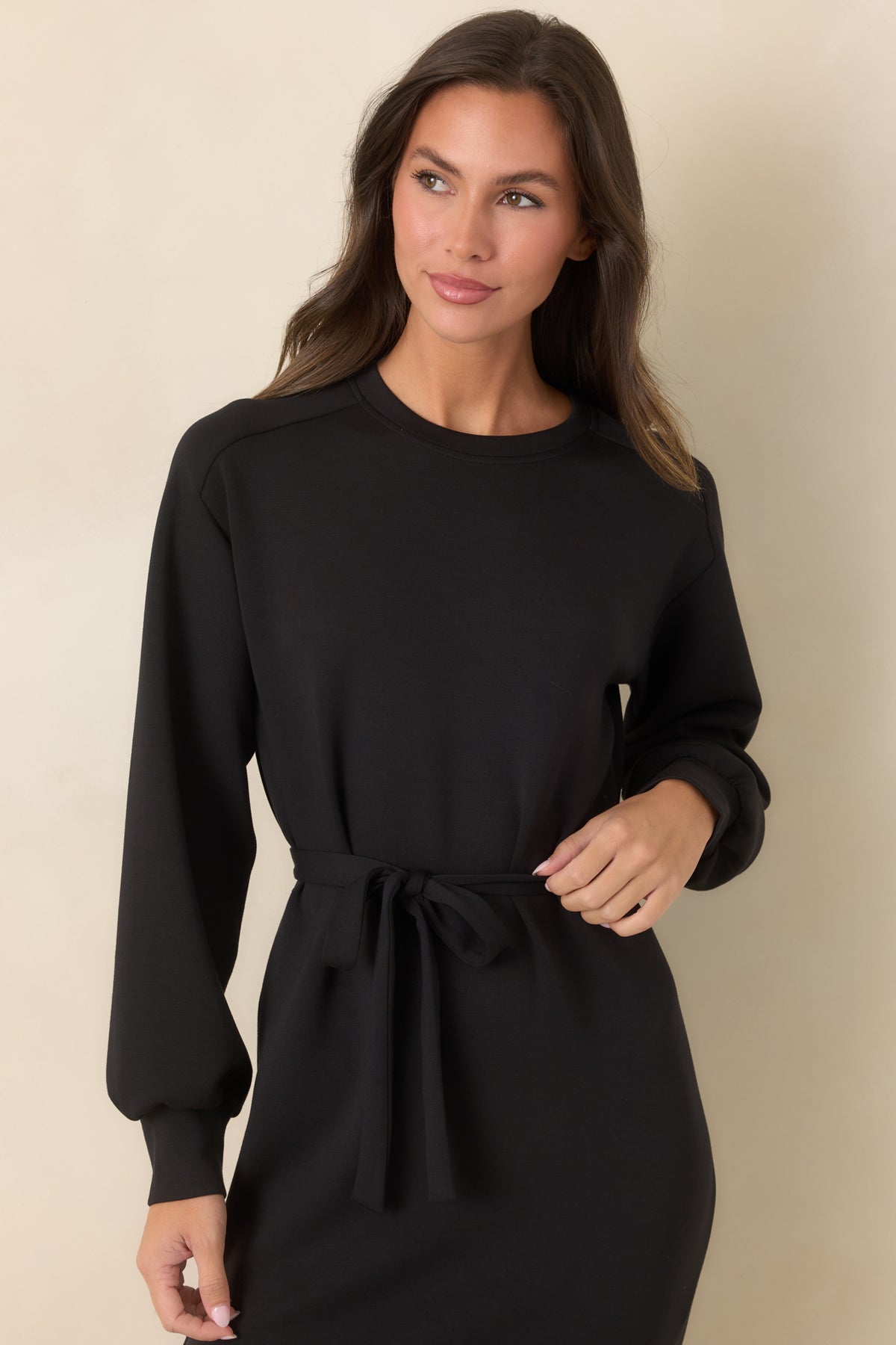 Close-up of the black crew neckline, long sleeve, and banded cuff detailing.