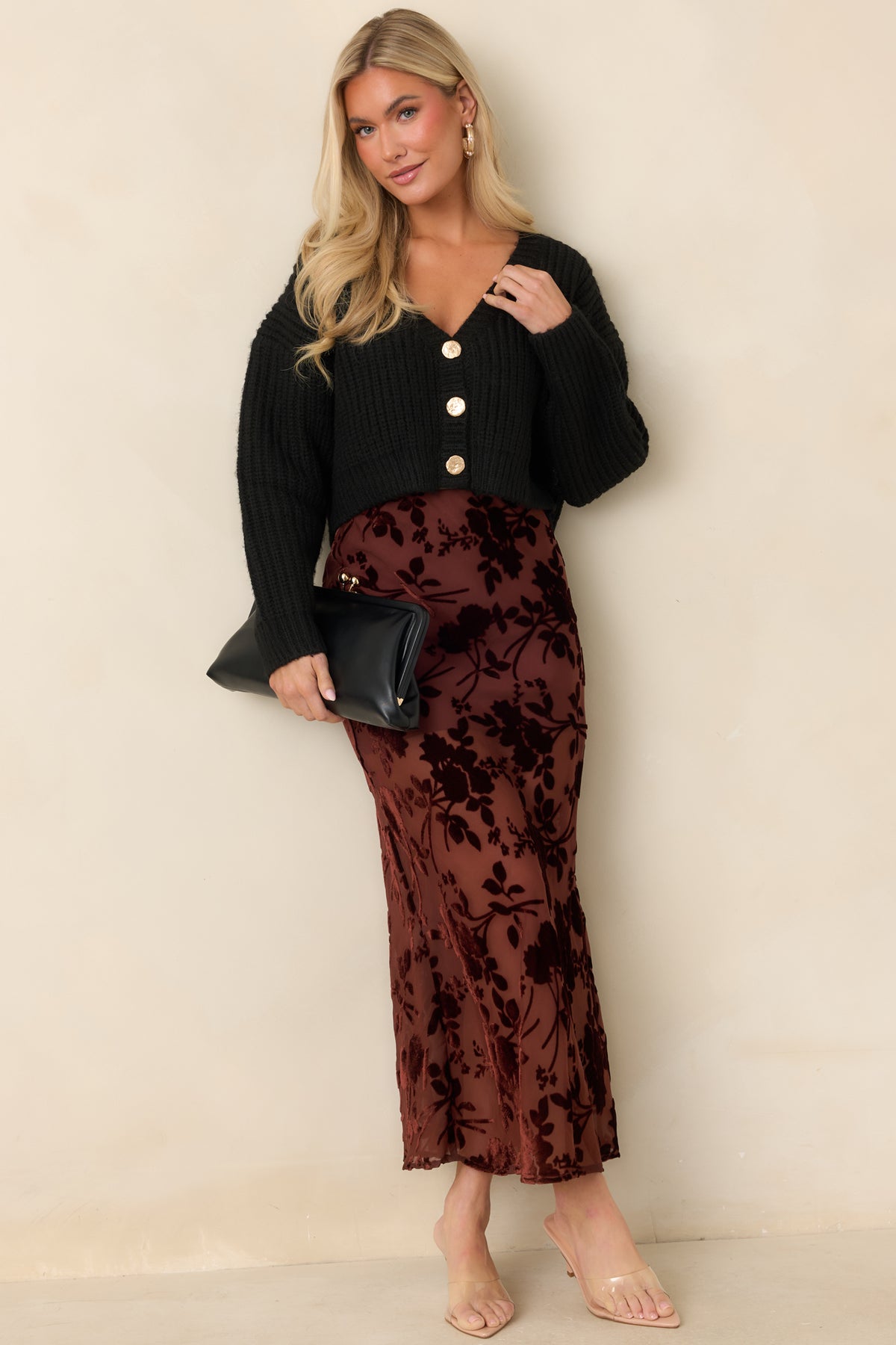 Black cropped cardigan with a deep V-neckline, chunky ribbed knit, and three gold-tone front buttons.