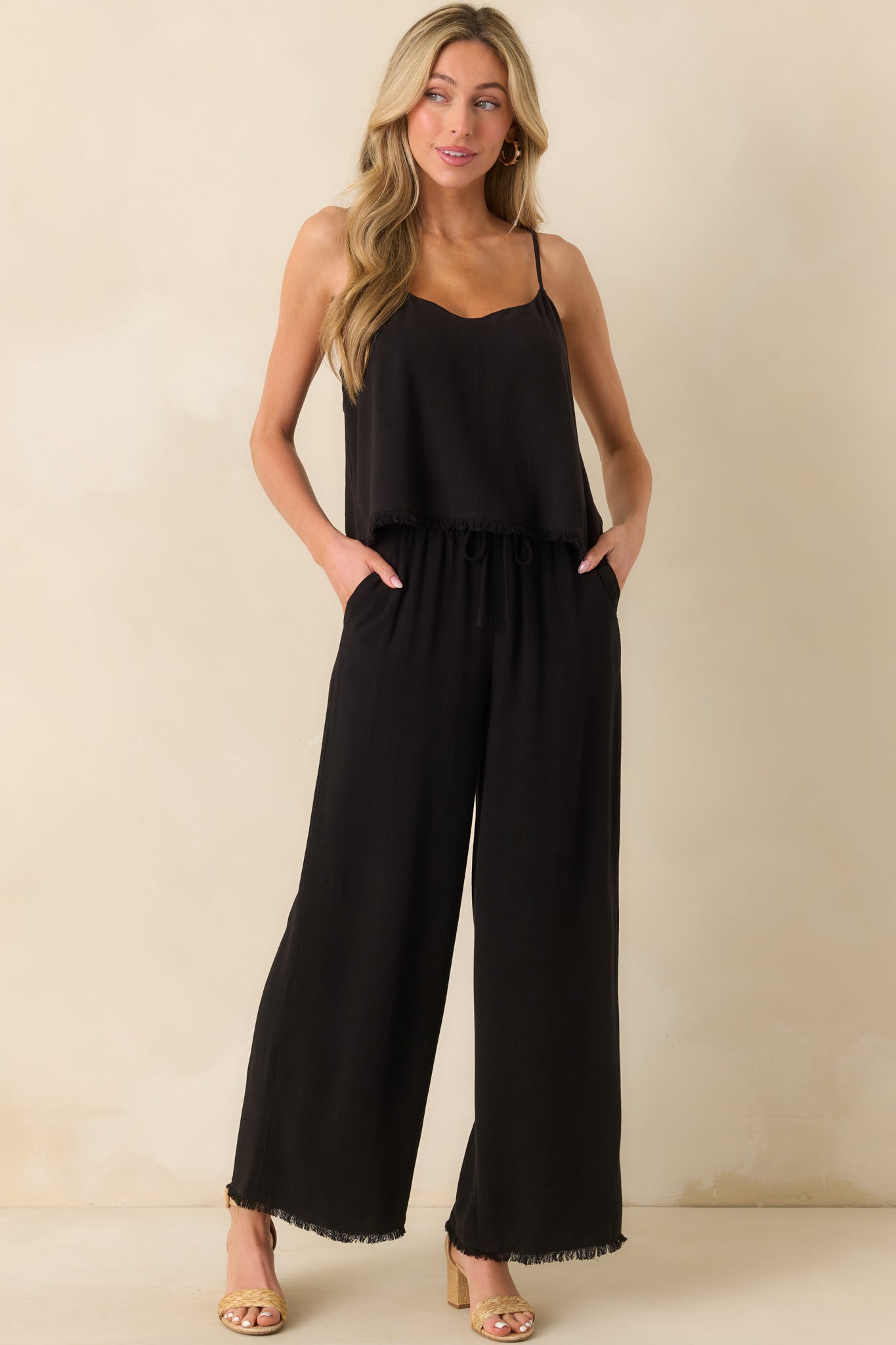 A full front view of the black tank top showing the scoop neckline, relaxed fit, and adjustable spaghetti straps.