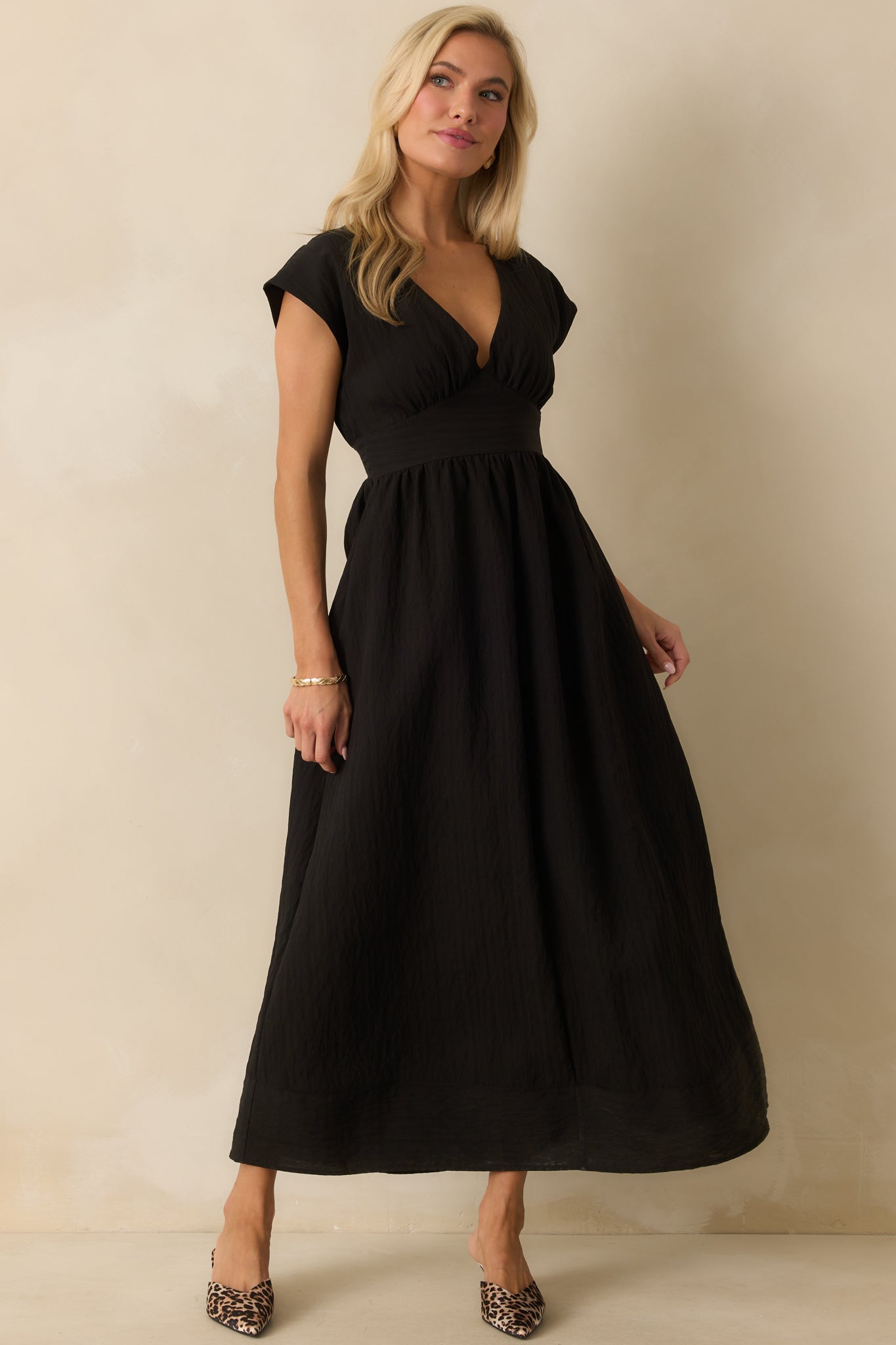 Sleek black dress with gathered bust, cap sleeves, and hidden back zipper closure.