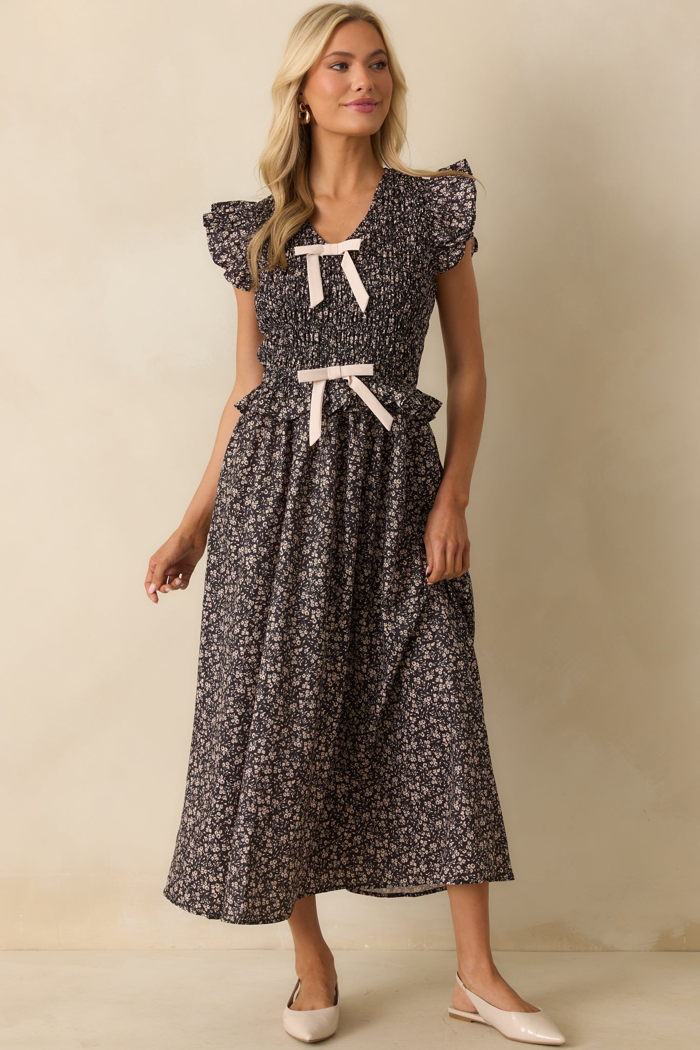Black dress highlighting a smocked bodice, bow front details, and floor-length silhouette.