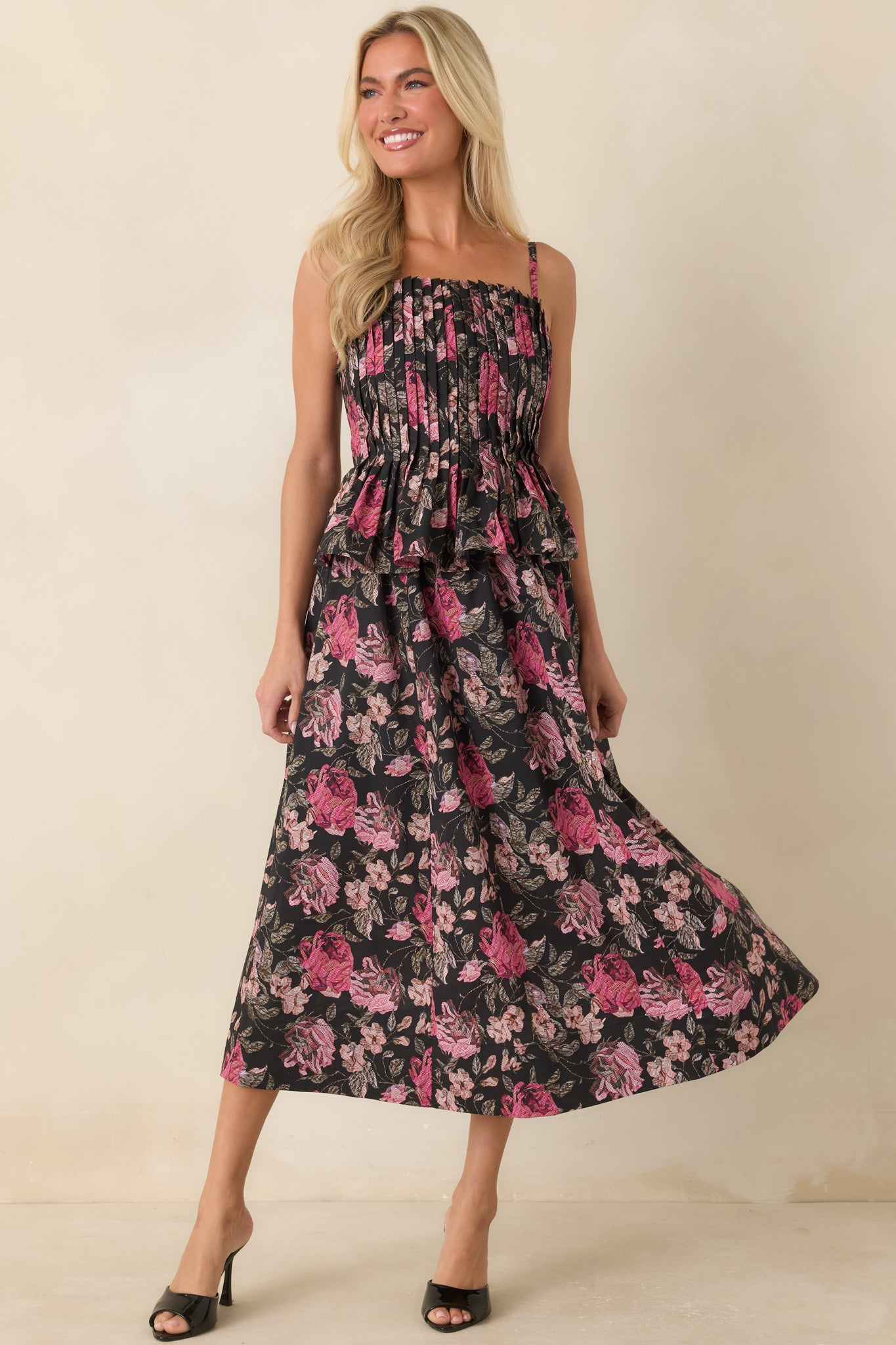 Black dress with pink floral motifs, a fitted bodice, and a graceful midi-length hemline.