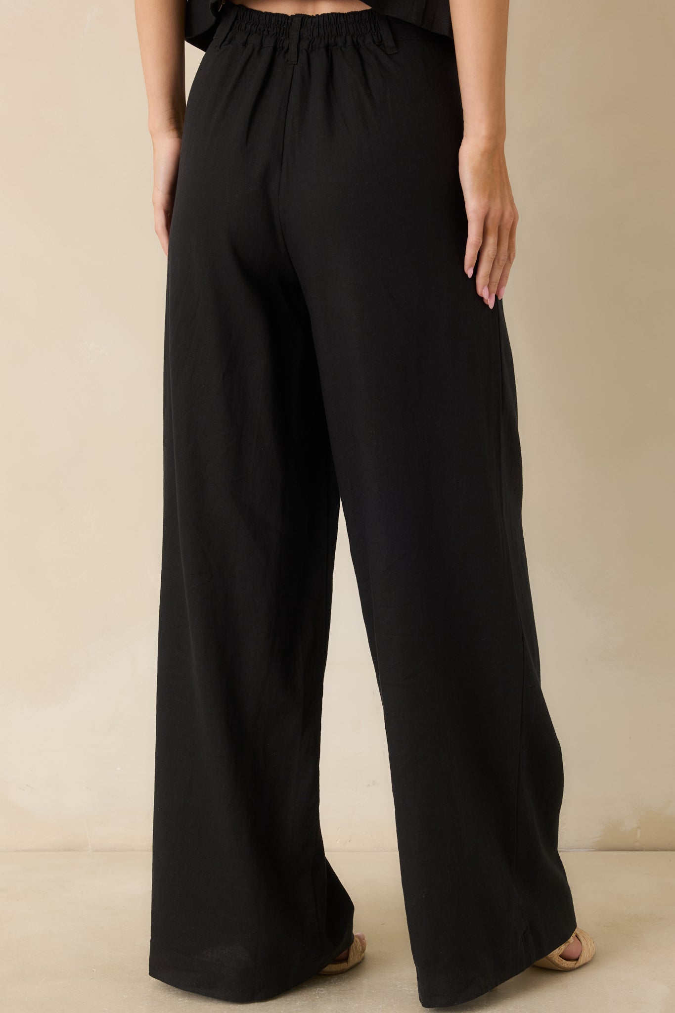 Rear view of the black linen blend pants featuring a comfortable elastic back waistband and a full-length straight-leg silhouette.