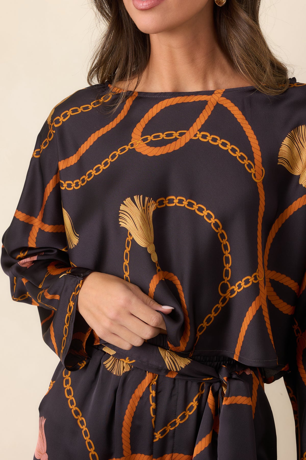 Close-up of the black satin-feel fabric featuring intertwined rust ropes, golden chains, and decorative tassel motifs.