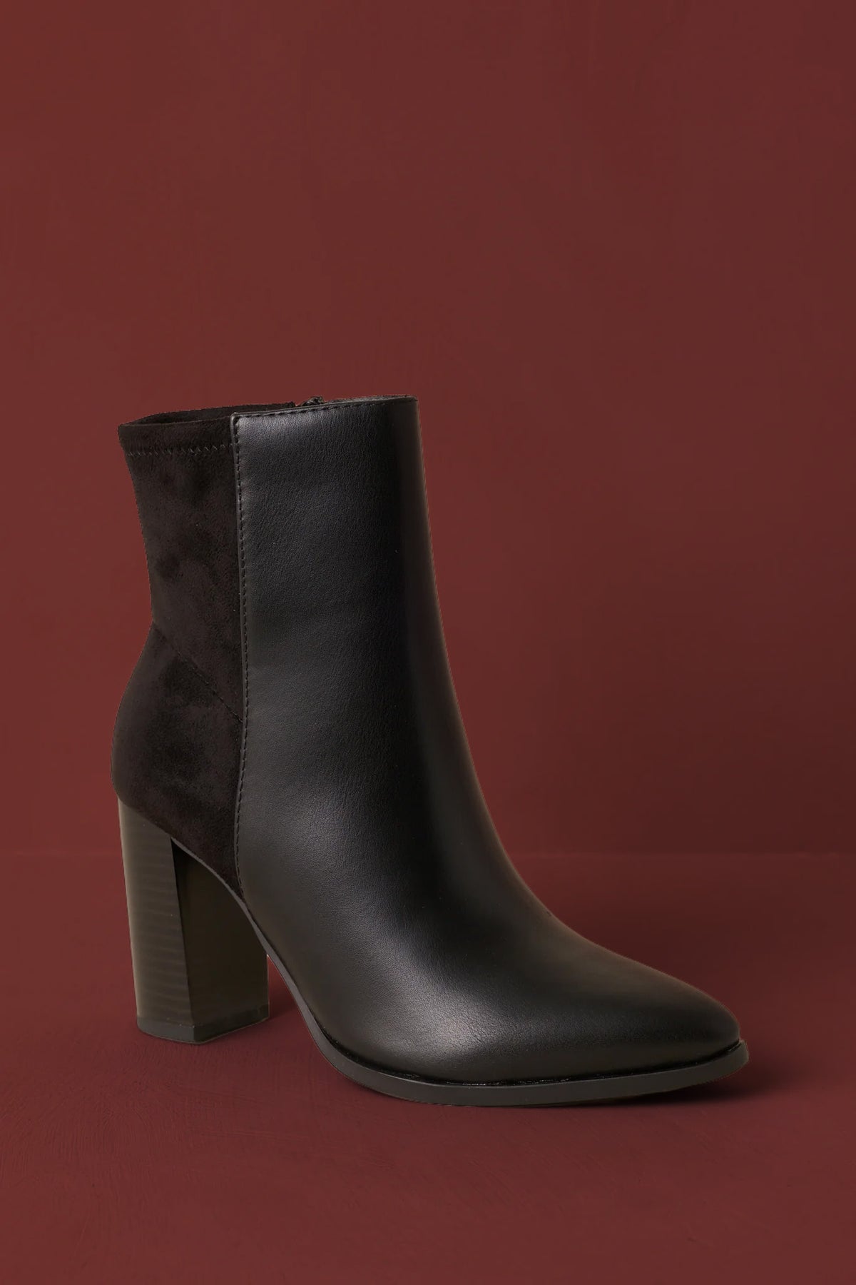 Black faux leather ankle boots showcasing a sleek silhouette, tonal faux suede panel, inner side zipper, and structured block heel.