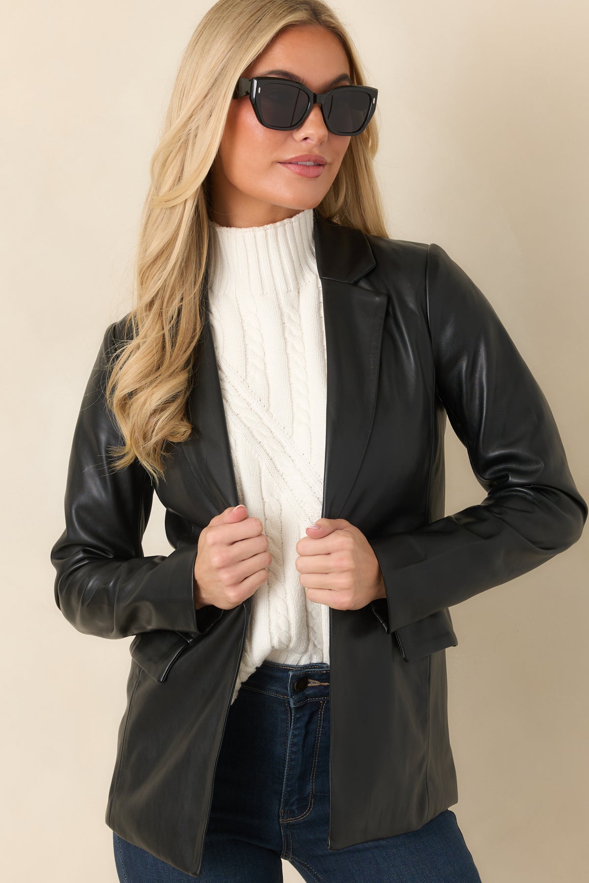 Hip-length hem and curved seams give the black faux leather blazer its defined shape.