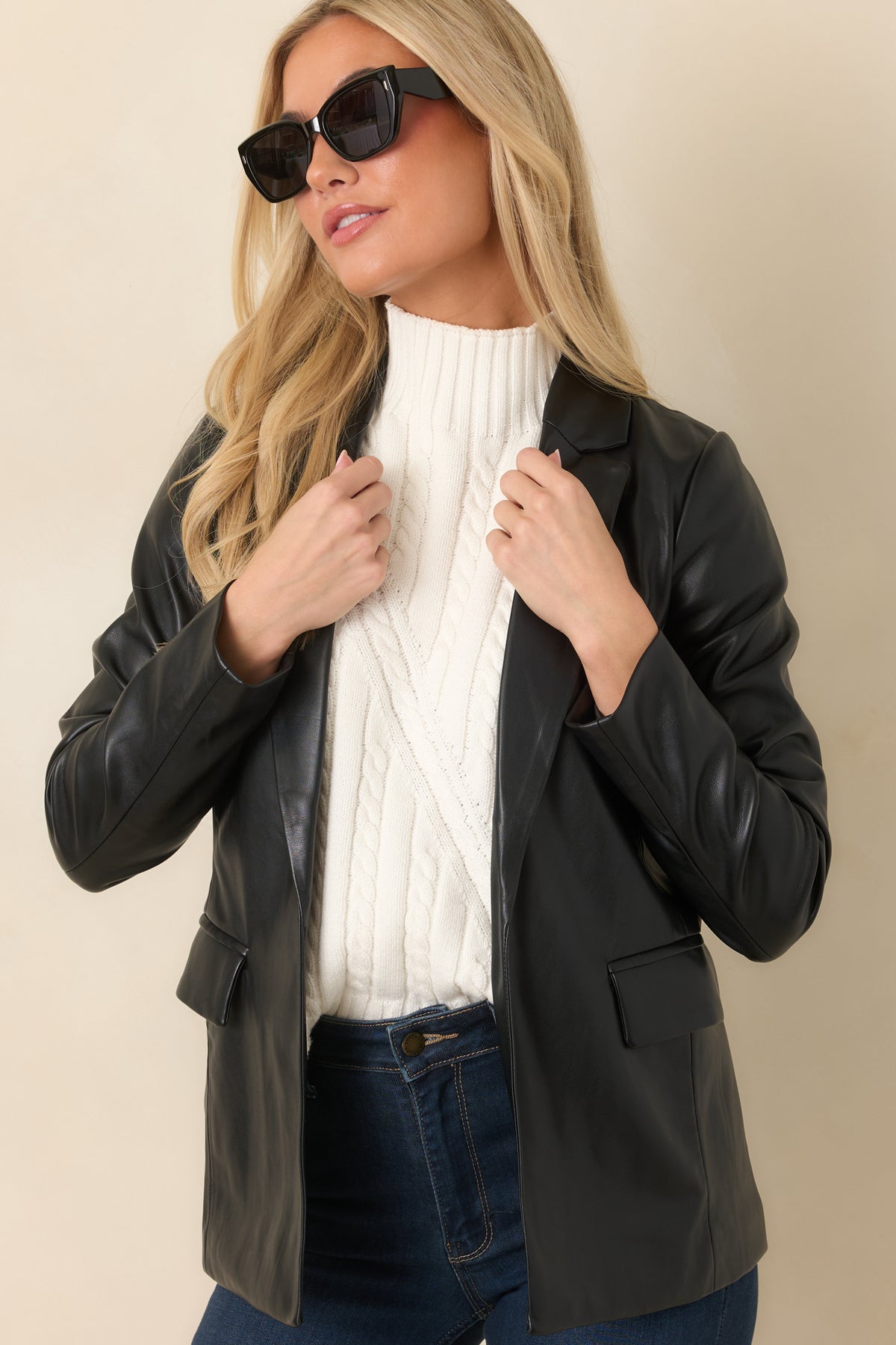 Notched lapels frame the neckline of this smooth black faux leather blazer.
