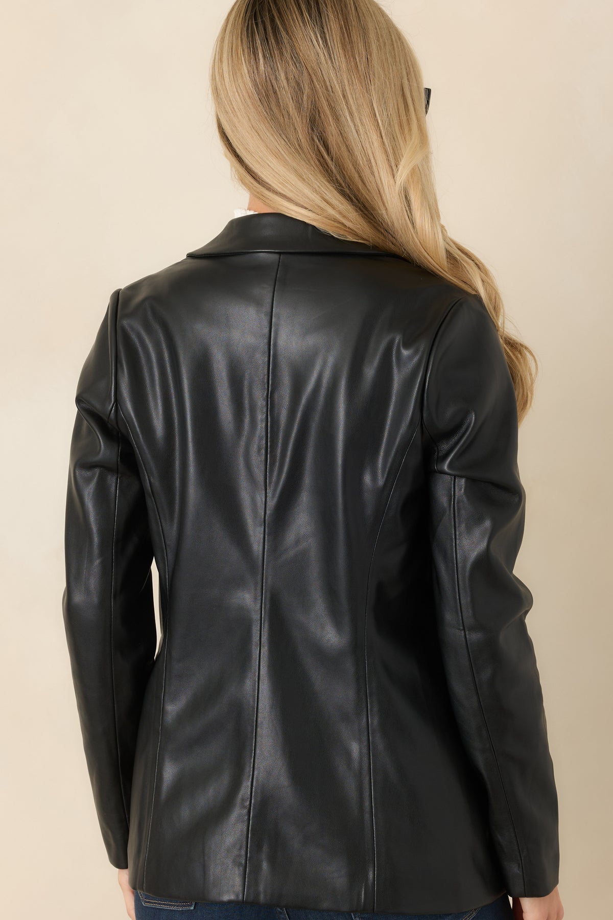 Smooth black faux leather blazer with a tailored back, curved waist seams, and a straight hip-length hem.