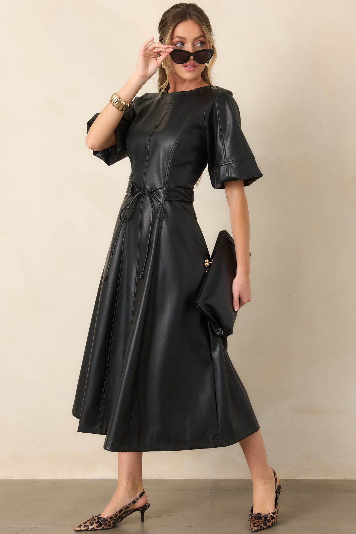 Black faux leather dress showcasing clean vertical seaming, a soft sheen finish, and A-line skirt.