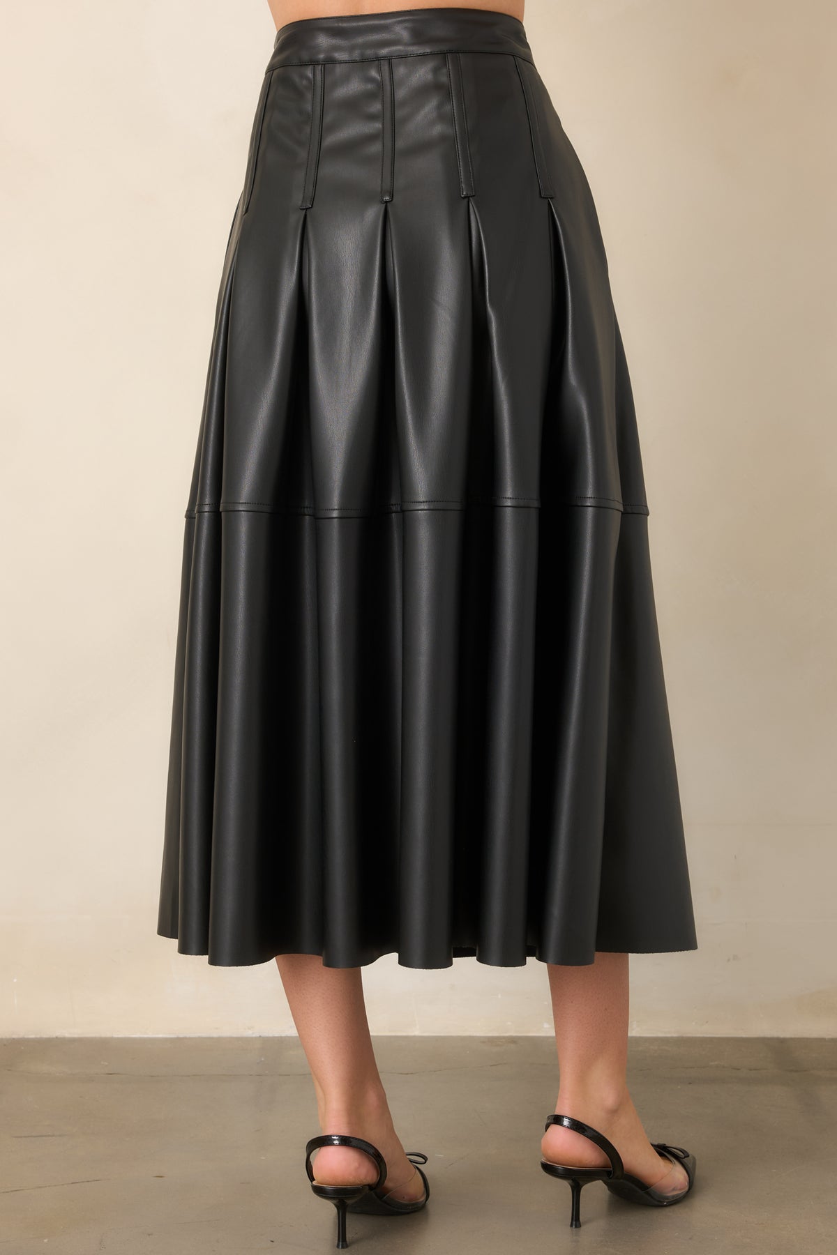 Rear view of the black faux leather midi skirt showing its full A-line silhouette and smooth waistband.