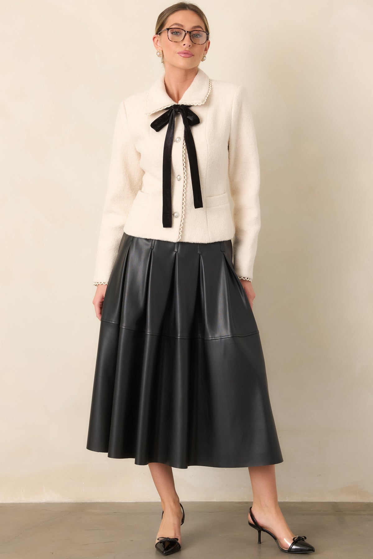 Black faux leather midi skirt with a smooth waistband and softly flowing A-line silhouette.
