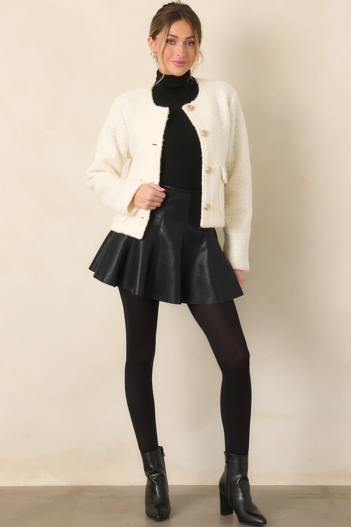 Black faux leather mini skirt with a fitted high-rise waist, paneled seams, and flared skater silhouette.
