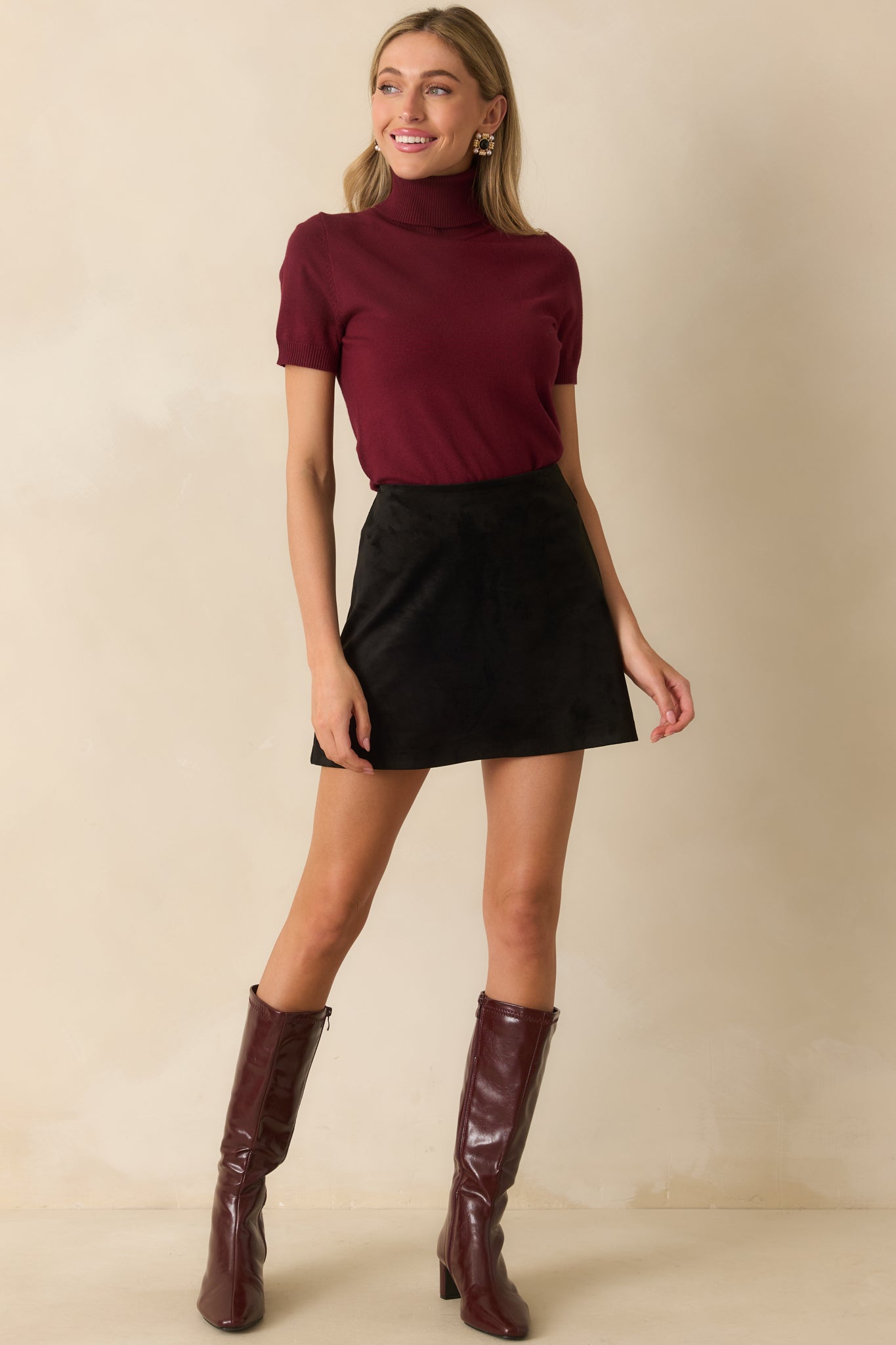 Black faux suede mini skirt with a fitted high-rise waist and A-line silhouette.