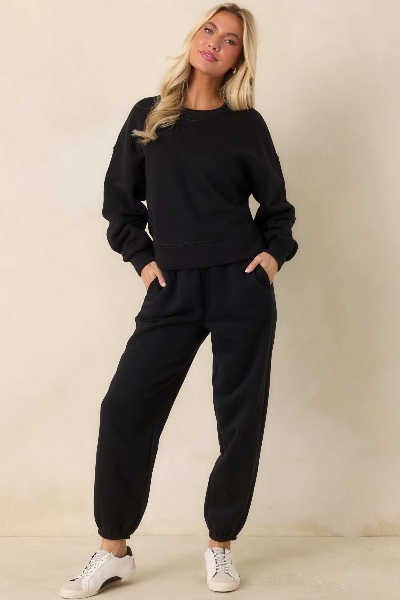 Black fleece joggers featuring a high-rise ribbed waistband, adjustable drawstring, roomy tapered legs, and elasticized cuffs.